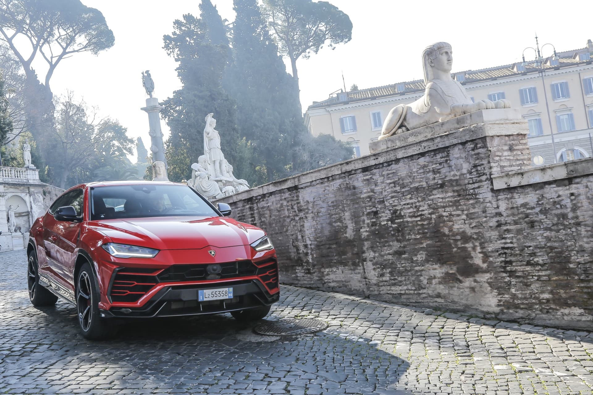 Lamborghini Urus rojo resaltando su agresiva estética frontal en una calle empedrada.