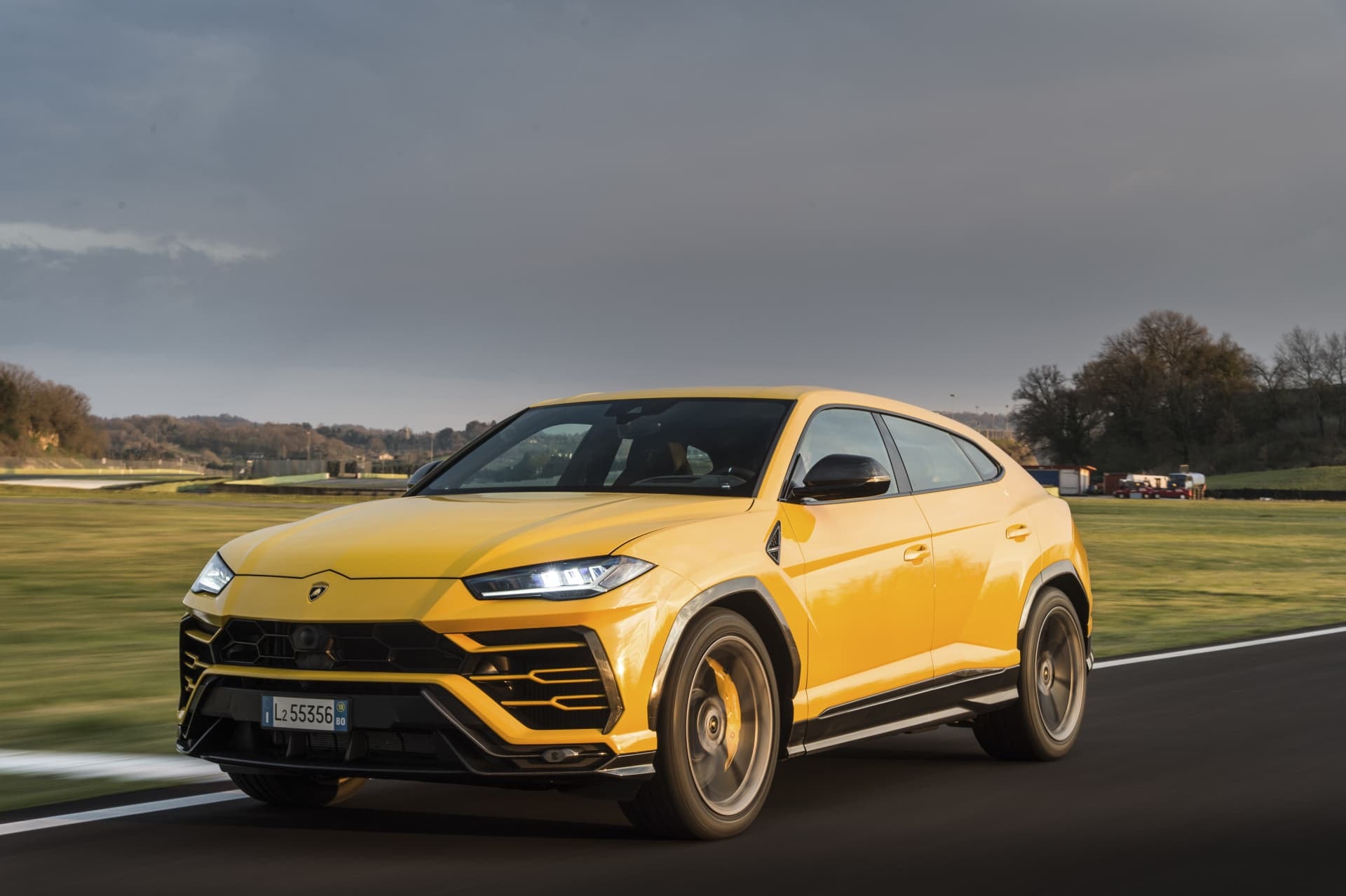Vista lateral dinámica del Urus en un vibrante color amarillo sobre la pista de carreras.