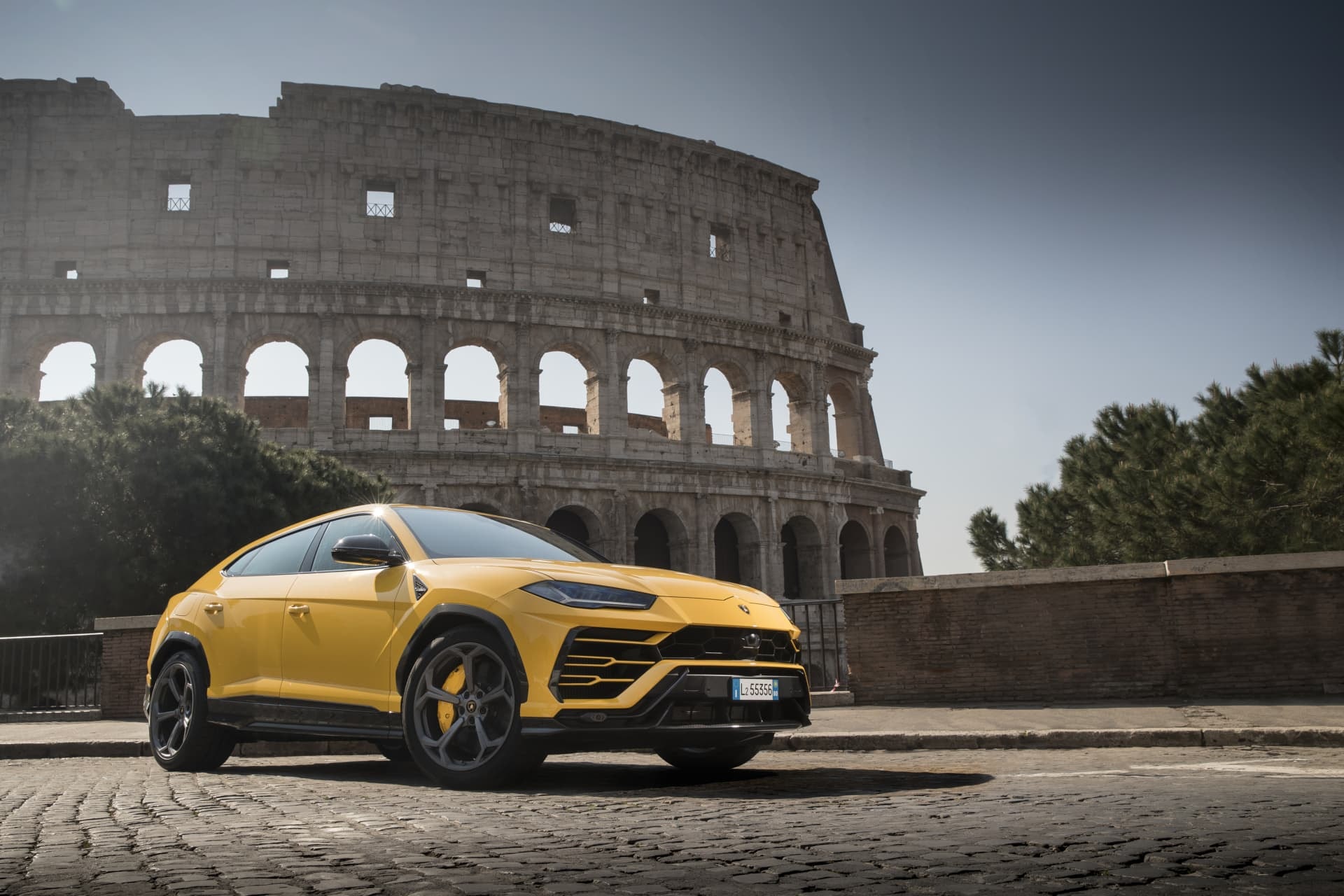 Perfil lateral del Urus amarillo ante el histórico Coliseo, una vista icónica.