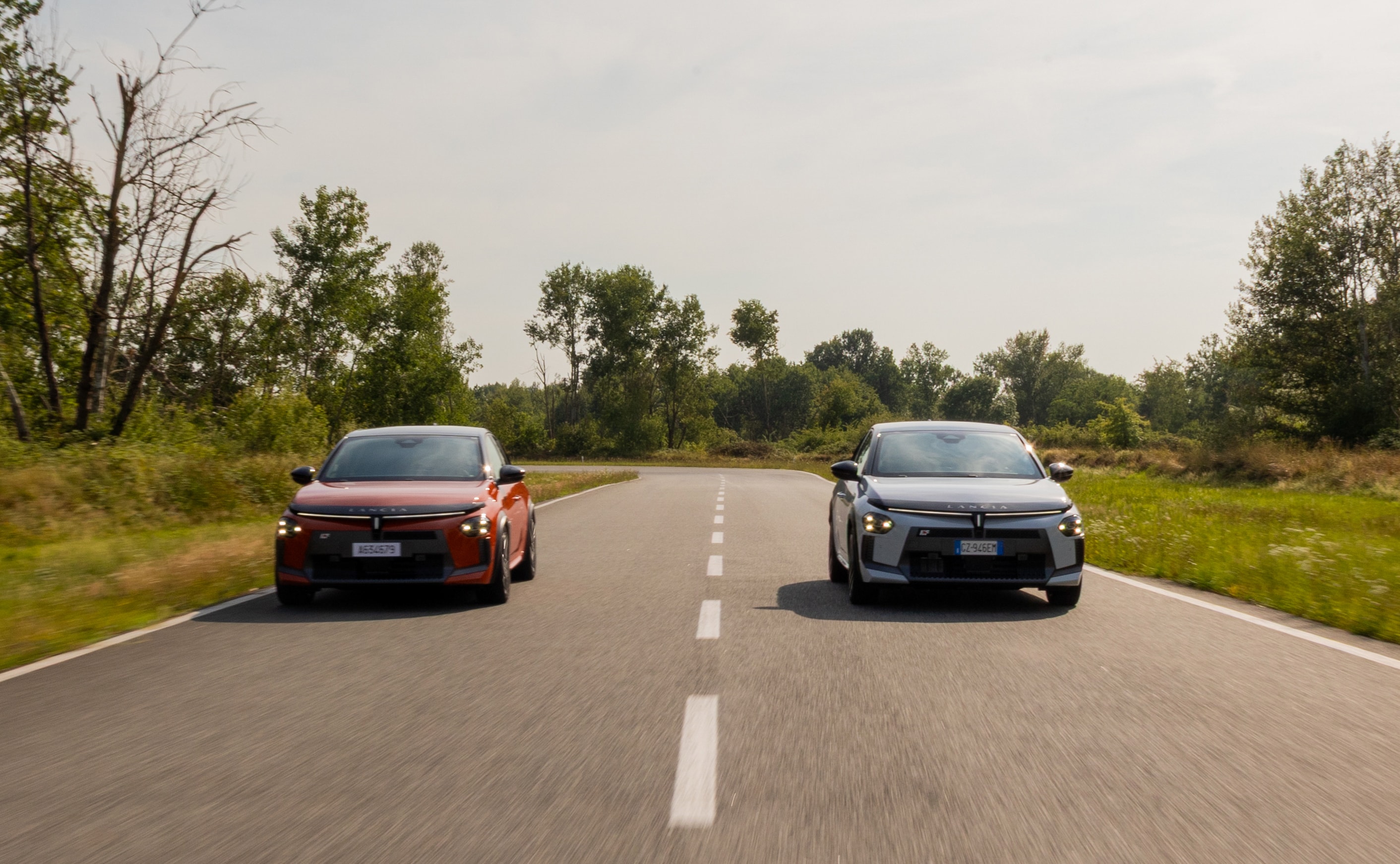 El Lancia Ypsilon naranja y blanco en una carretera despejada, mostrando su dinamismo.