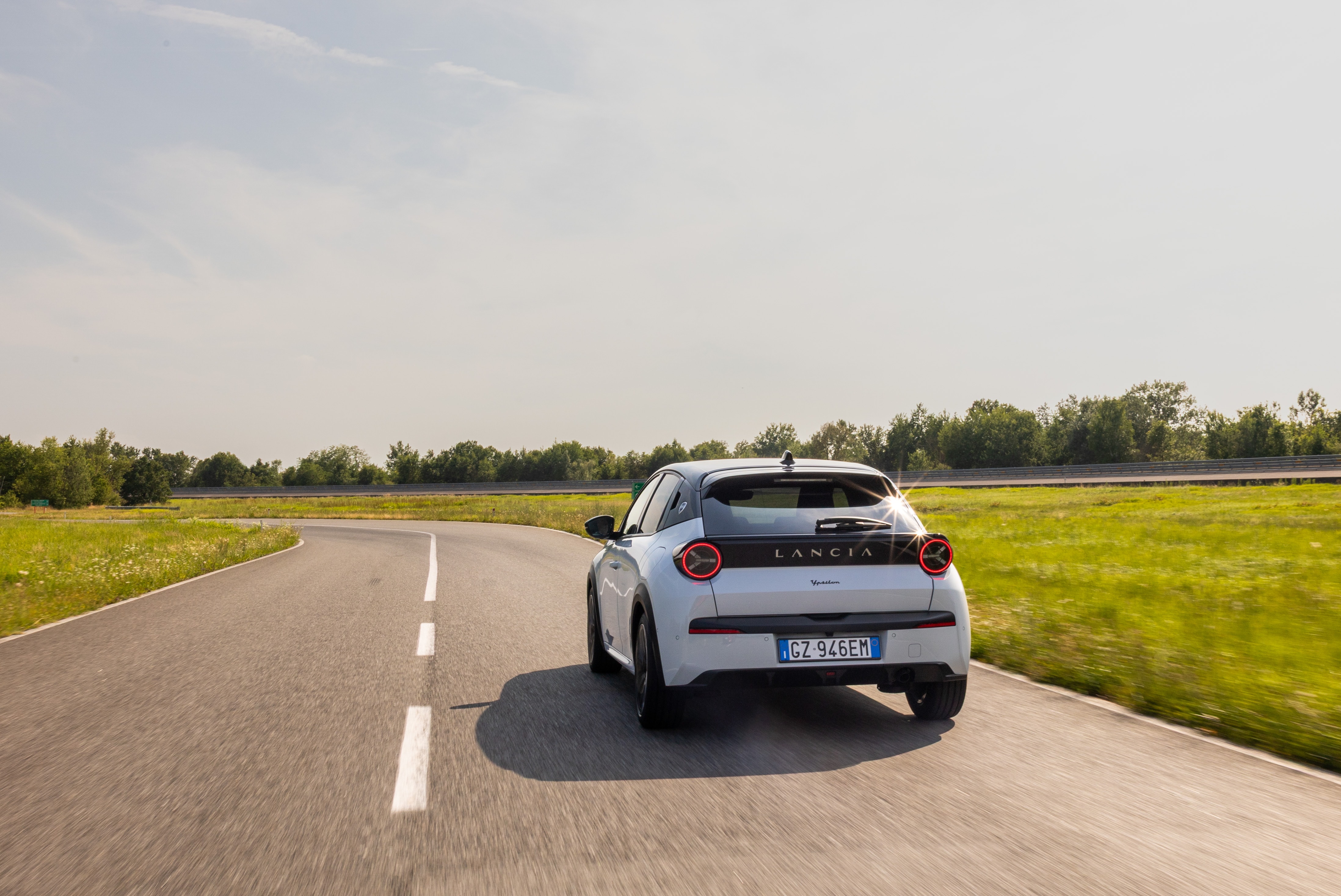 Perspectiva trasera del Lancia Ypsilon en un paisaje primaveral.