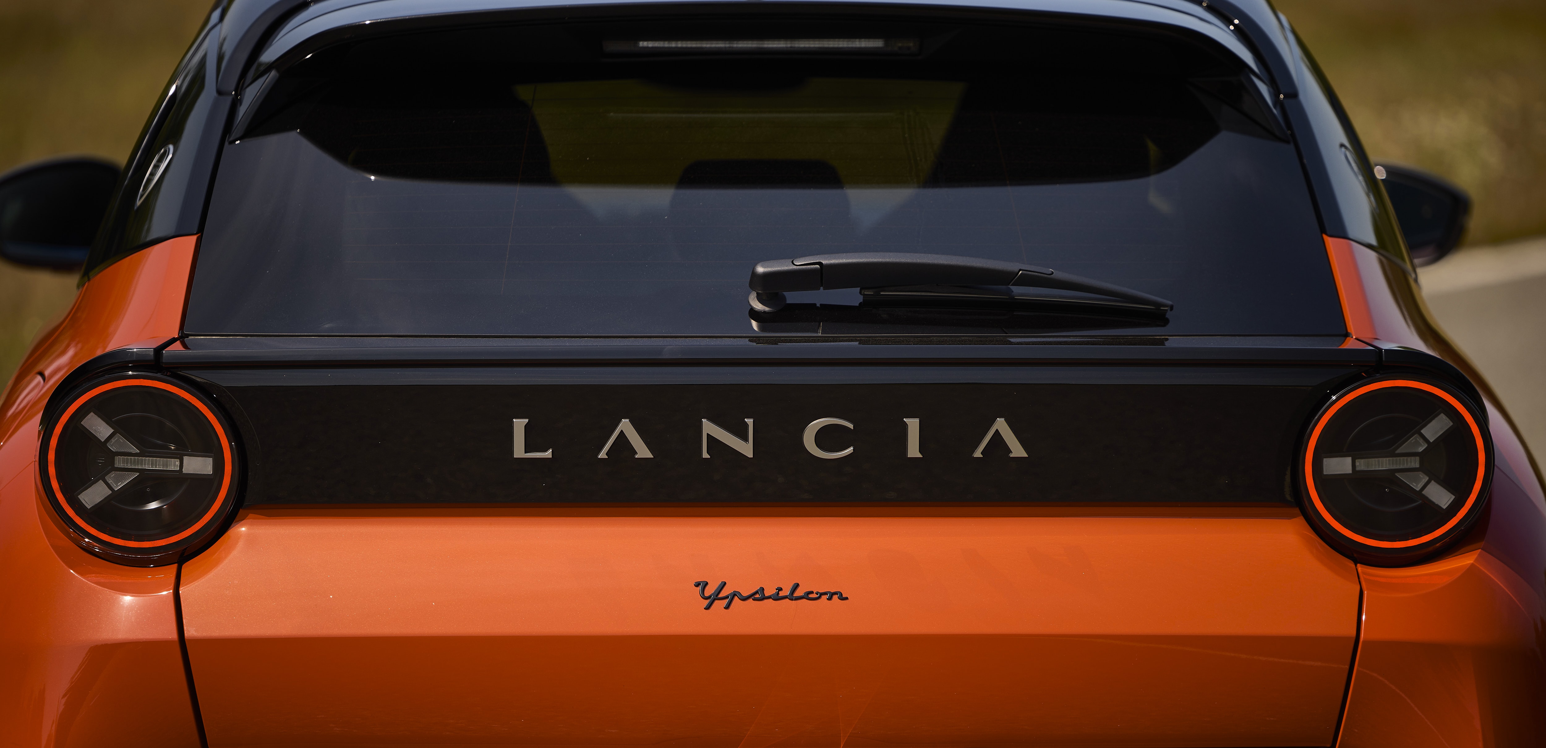 Vista trasera del Lancia Ypsilon, destacando su iluminación y logo.