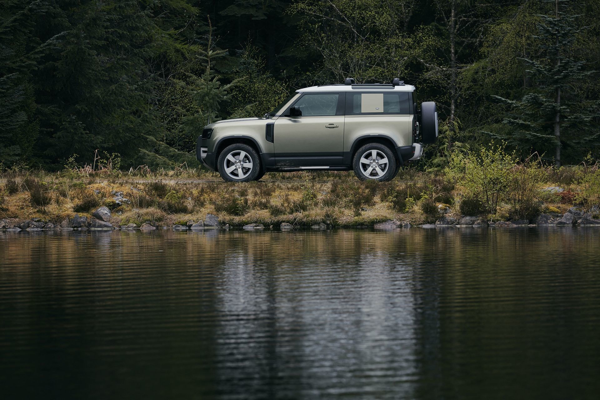 Land Rover Defender junto a lago, reflejo impecable