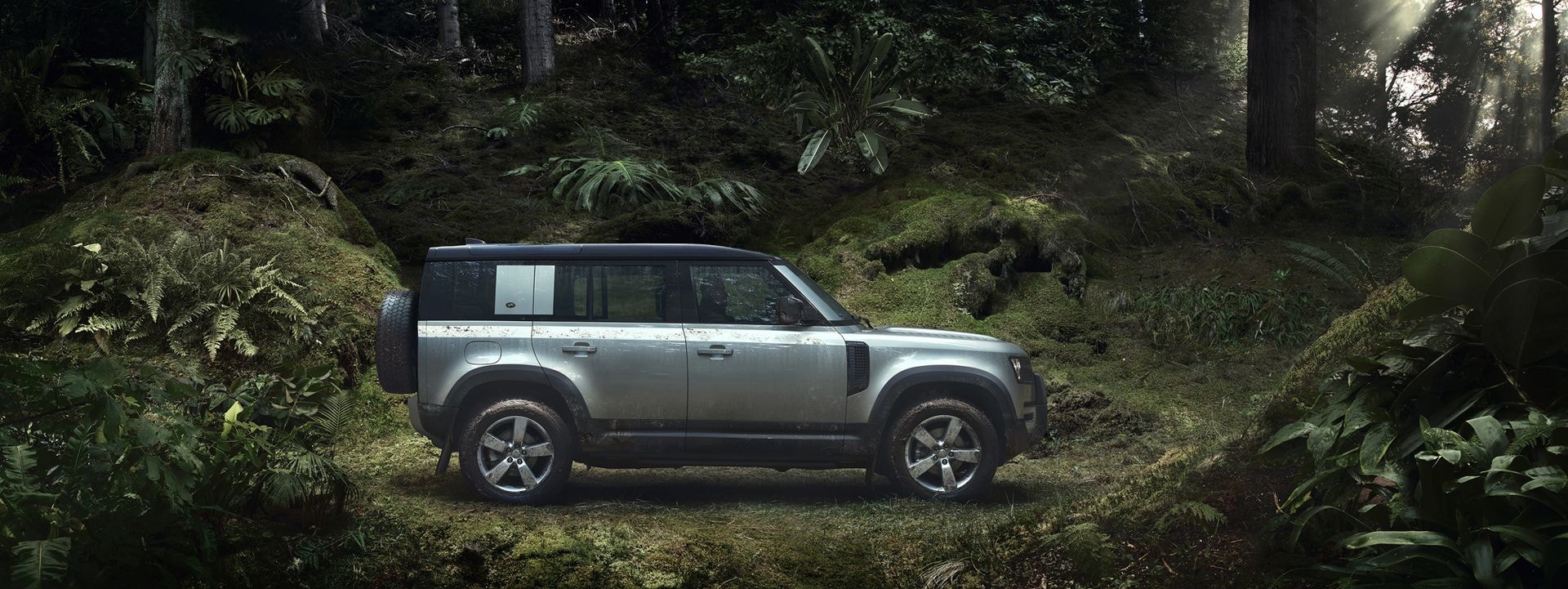 Land Rover Defender en un tranquilo sendero de bosque.