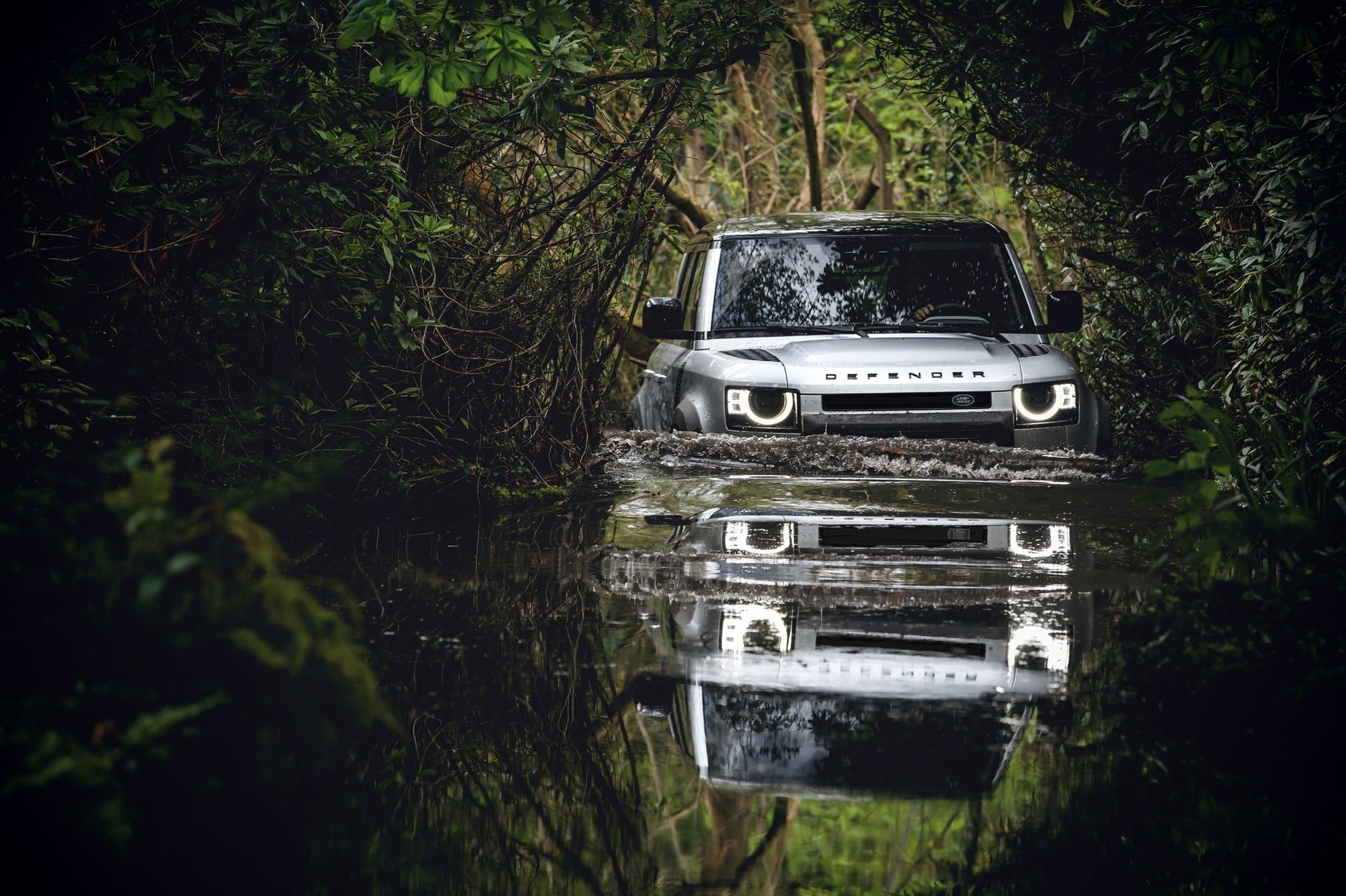 Land Rover Defender avanzando por un camino inundado.