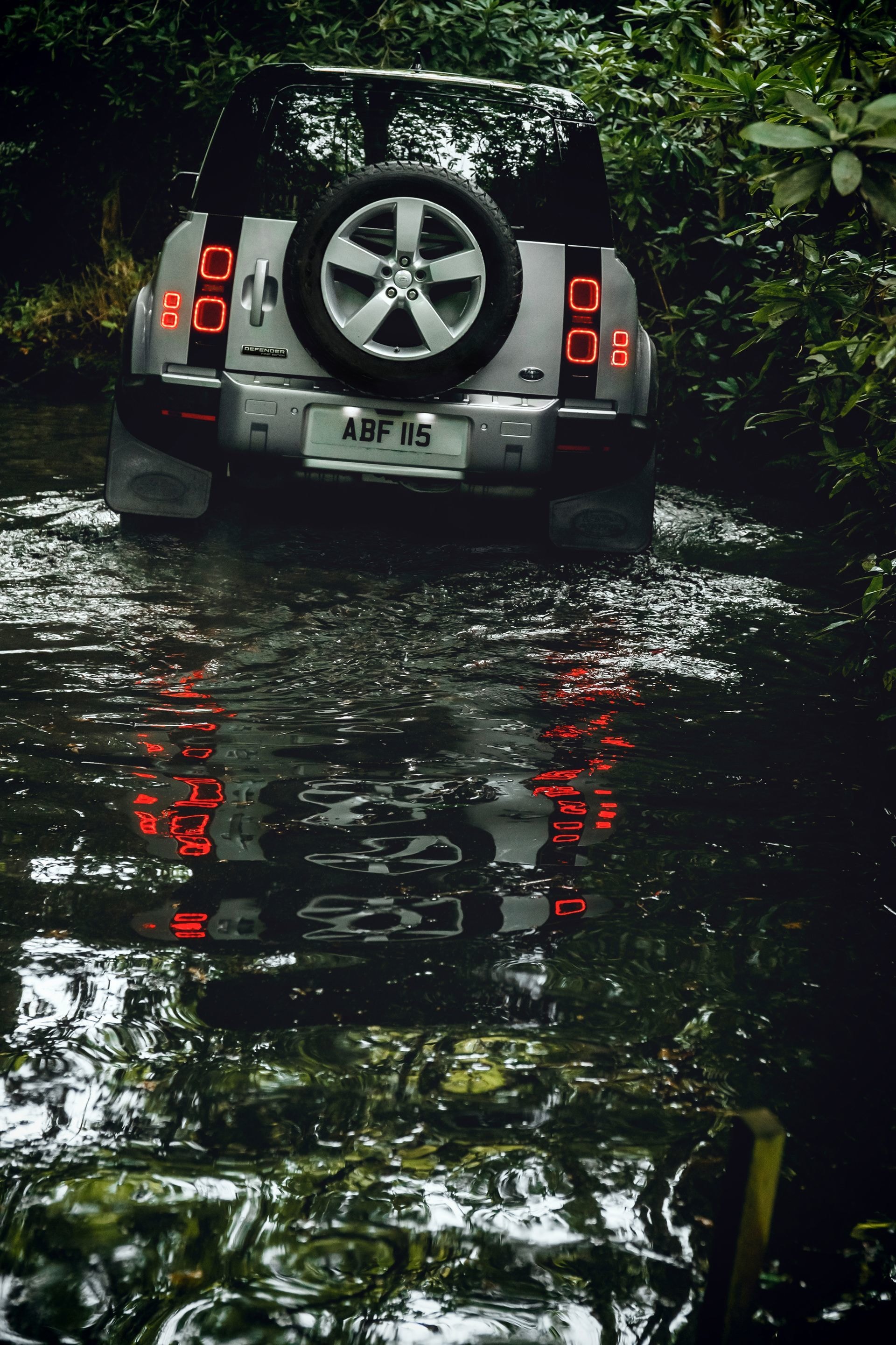 Perspectiva trasera del Defender con reflejo en el agua.