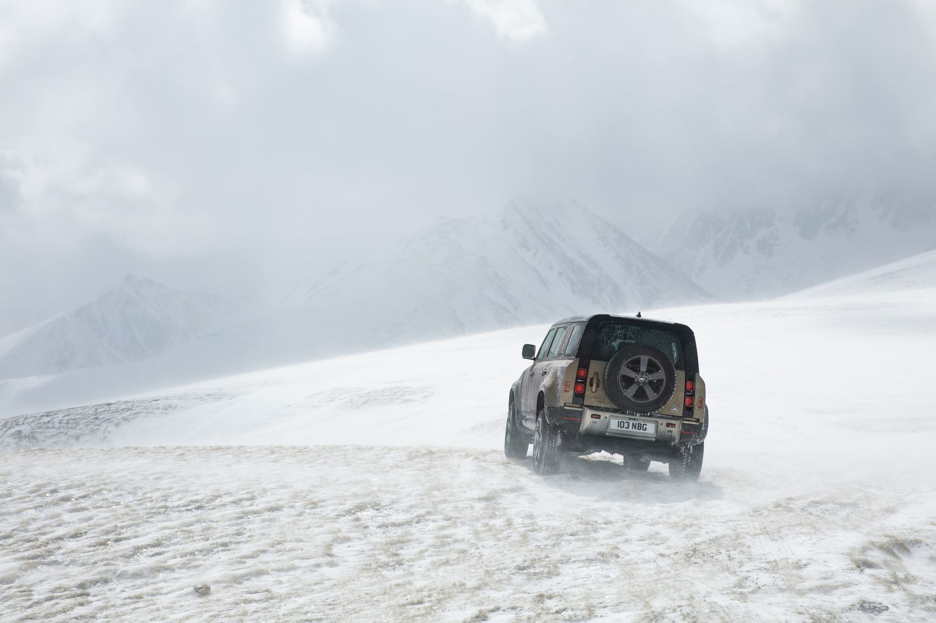 Lateral del Defender desplazándose por terreno nevado, mostrando su capacidad off-road