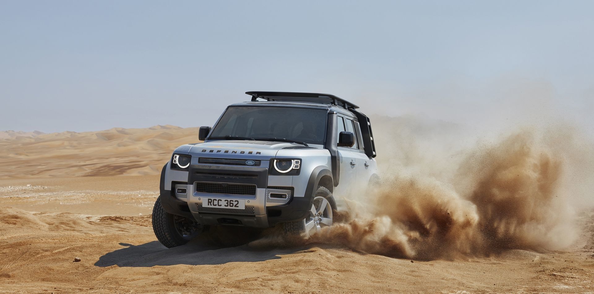 Land Rover Defender superando con destreza dunas arenosas.