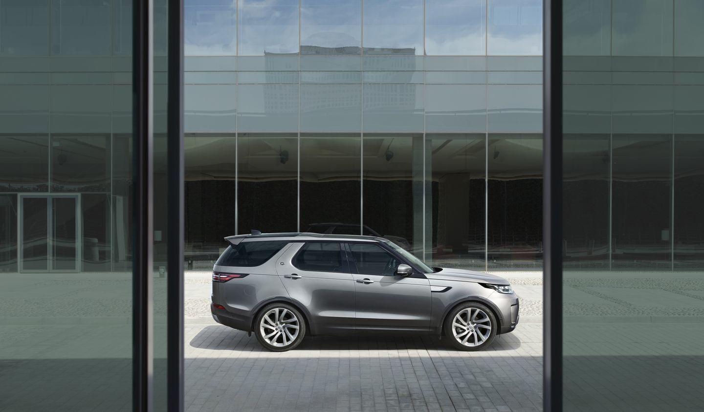 Perfil del Land Rover Discovery reflejado en vidrio urbano.