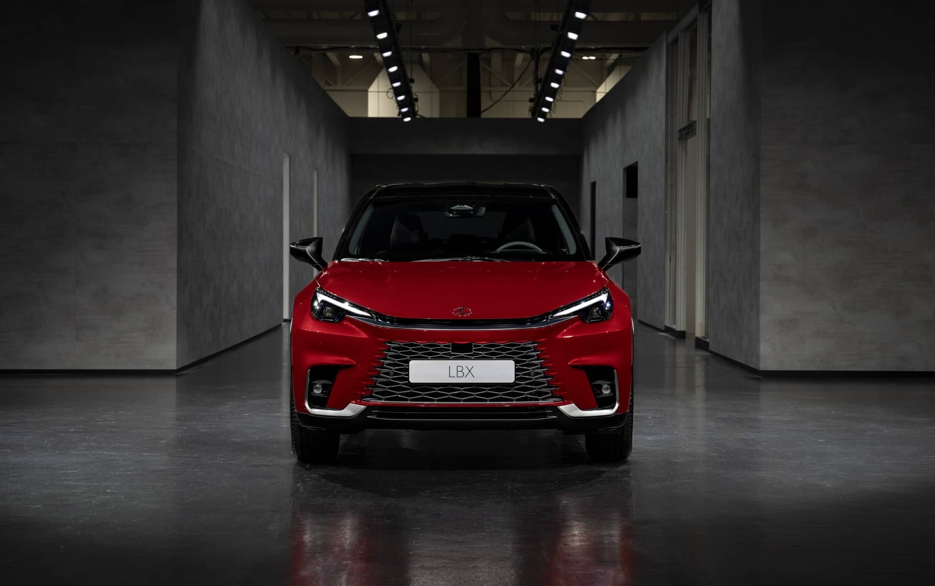 Vista frontal del Lexus LBX en rojo, enfocada en la parrilla y ópticas en detalle.