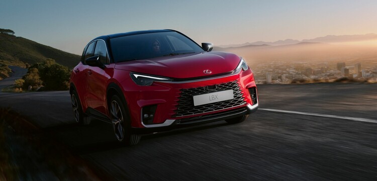 Dynamic view of a Lexus LBX driving at dawn, highlighting the car's road presence and sleek design. Dynamic view of a Lexus LBX driving at dawn, highlighting the car's road presence and sleek design.