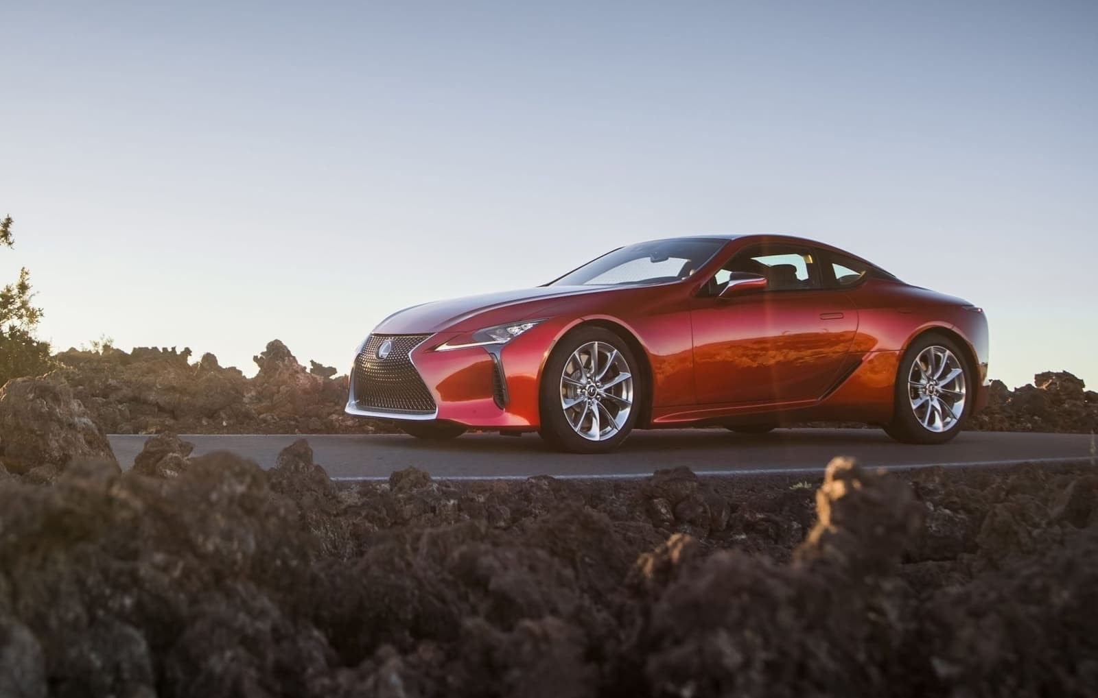 Lexus LC híbrido perfilado ante un fondo de terreno volcánico, mostrando su silueta.