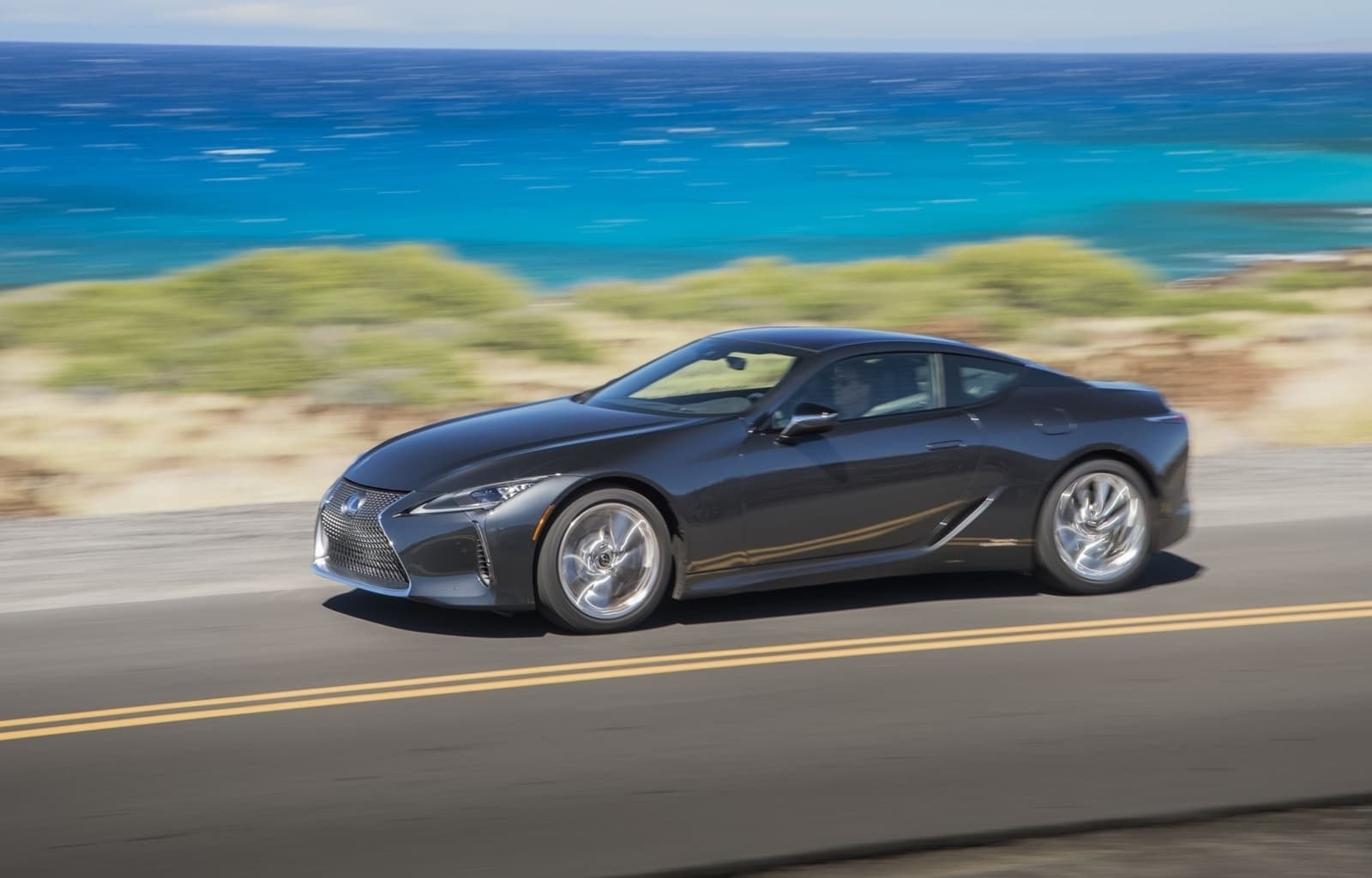Lexus LC híbrido captado desde un ángulo lateral en plena carrera, mostrando su potencia y elegancia.
