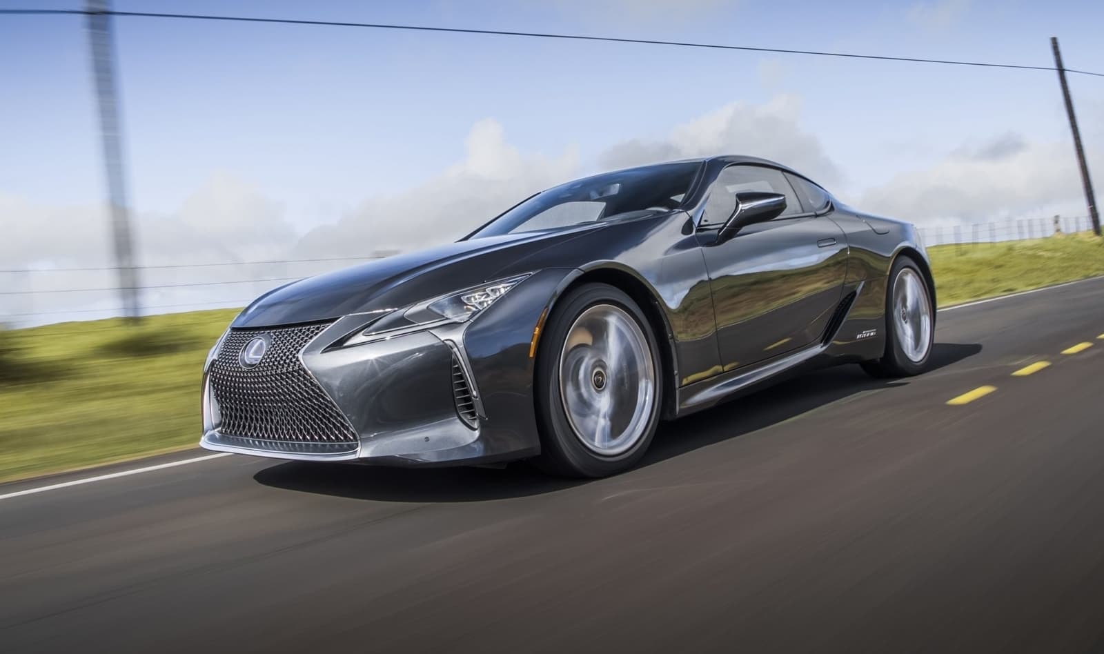 Perfil dinámico en carretera del Lexus LC híbrido, encarnando la esencia de un coupé deportivo.
