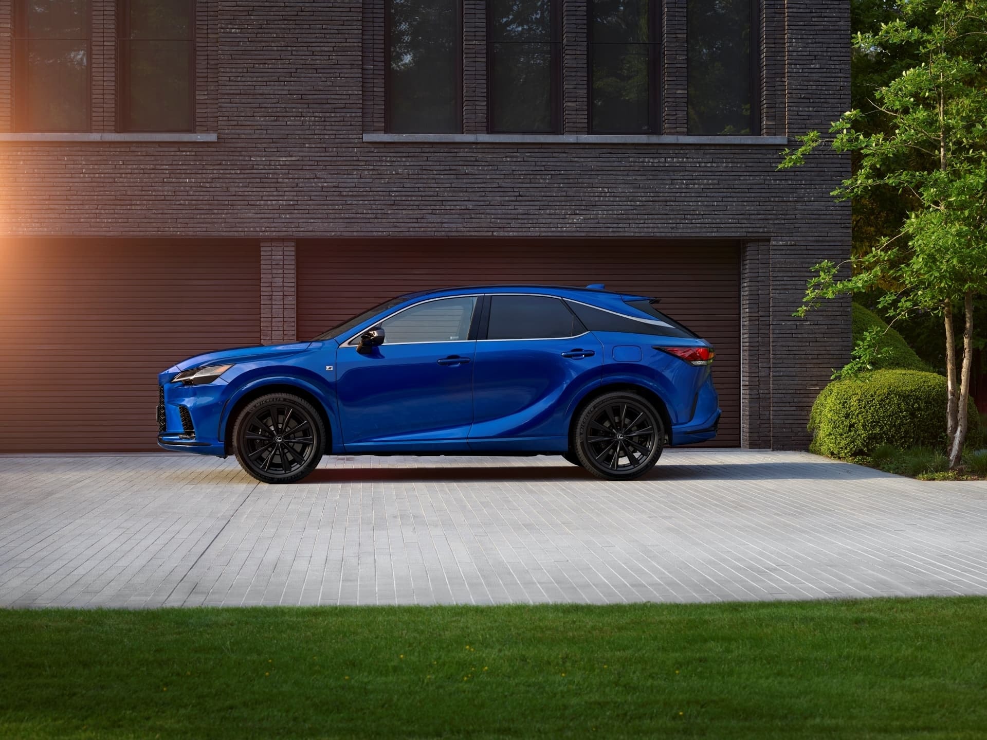 Lexus RX híbrido aparcado frente a una vivienda moderna.