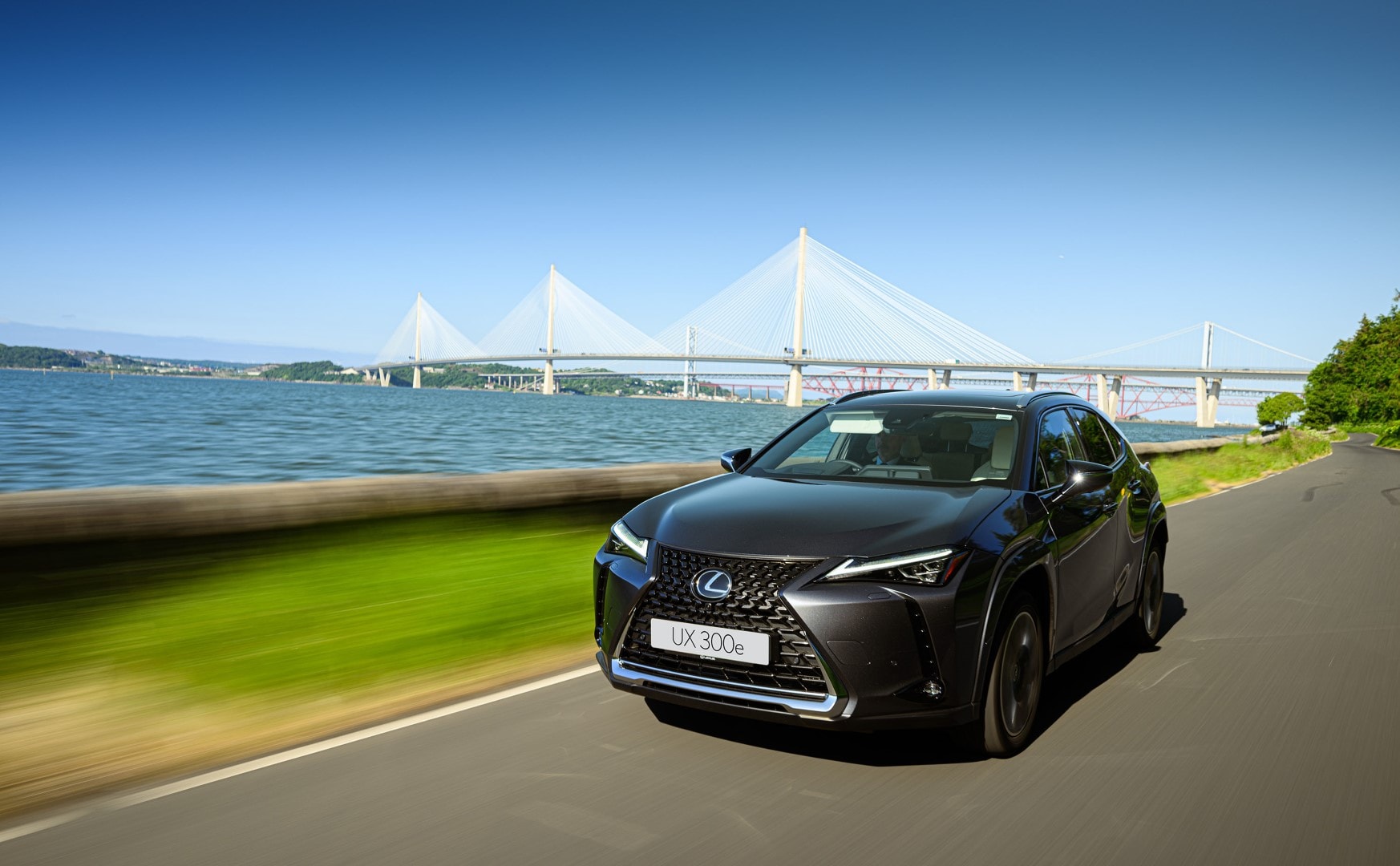 Dinamismo y diseño del Lexus UX300e capturados con un puente moderno al fondo.