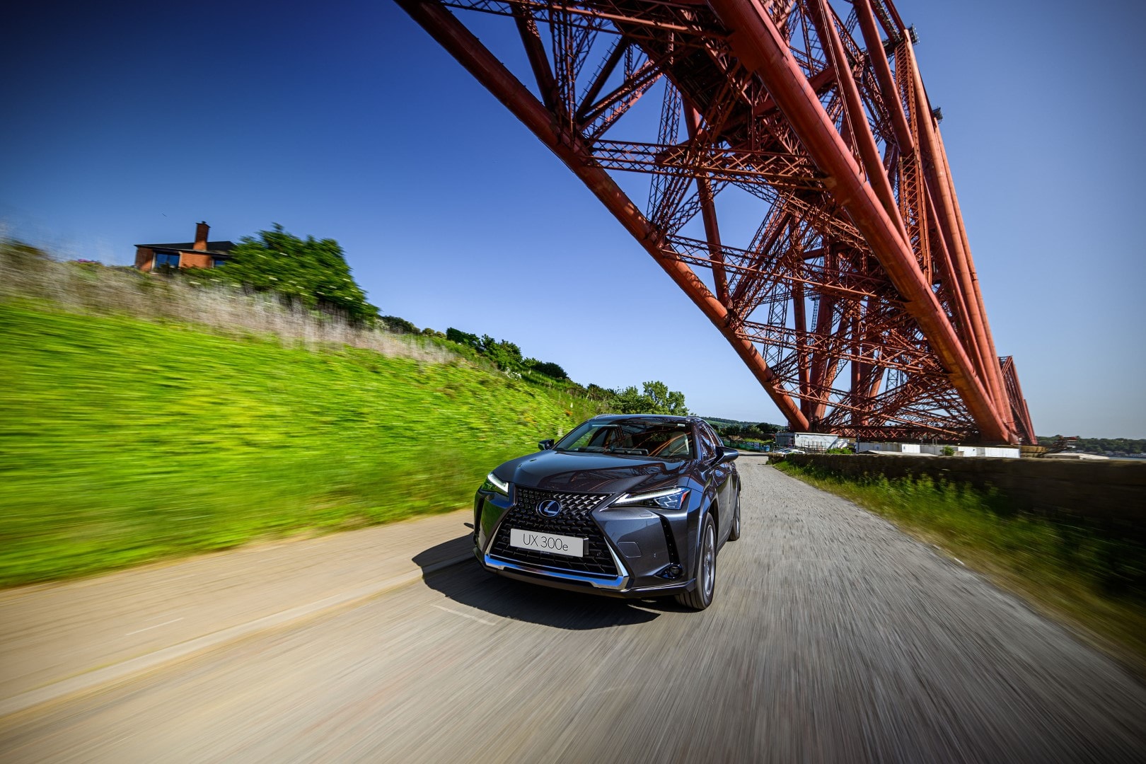 Lexus UX300e en movimiento, con vista lateral y el puente en el fondo.