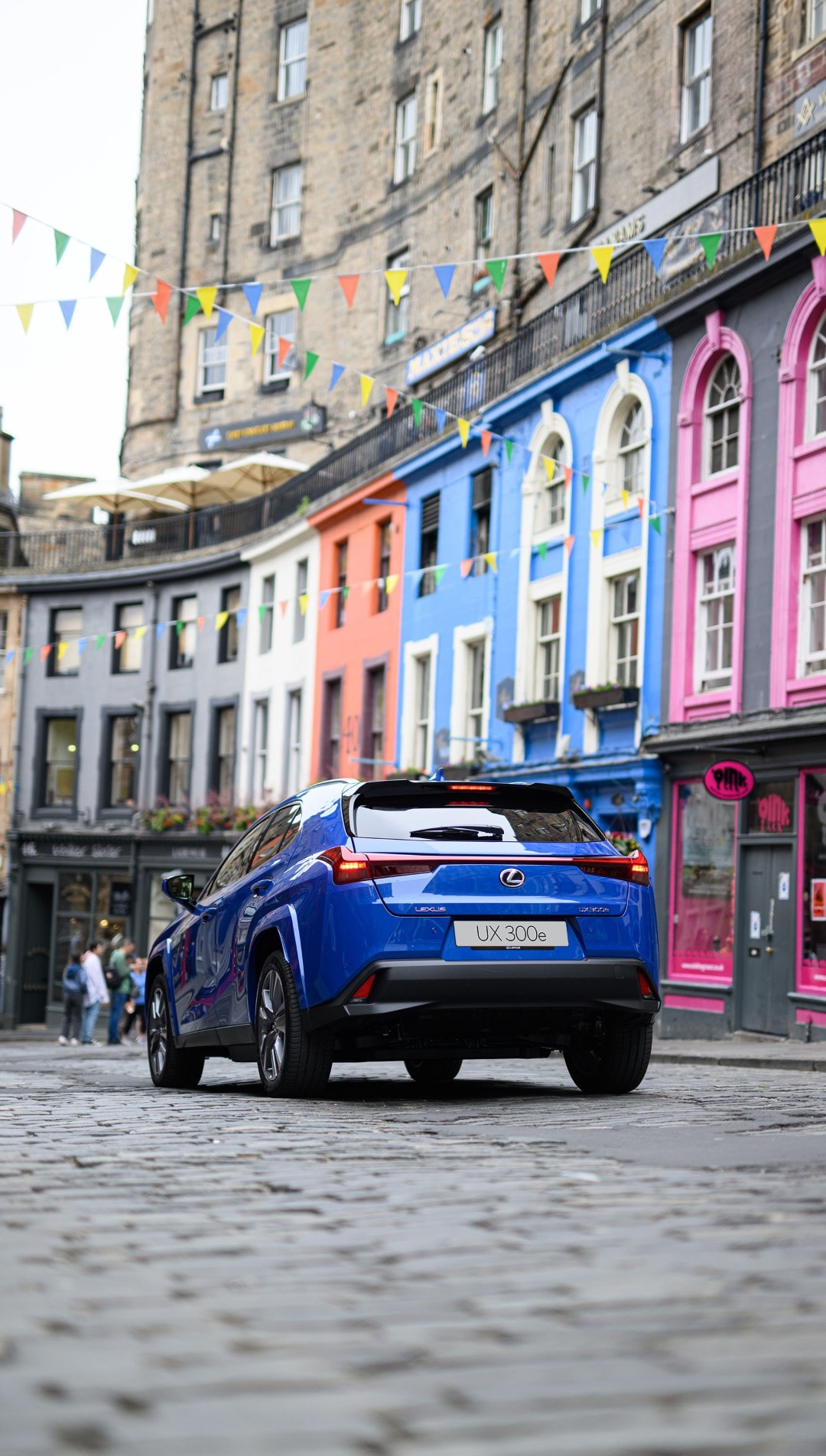 Vista trasera del Lexus UX300e que contrasta con las fachadas coloridas de la calle.