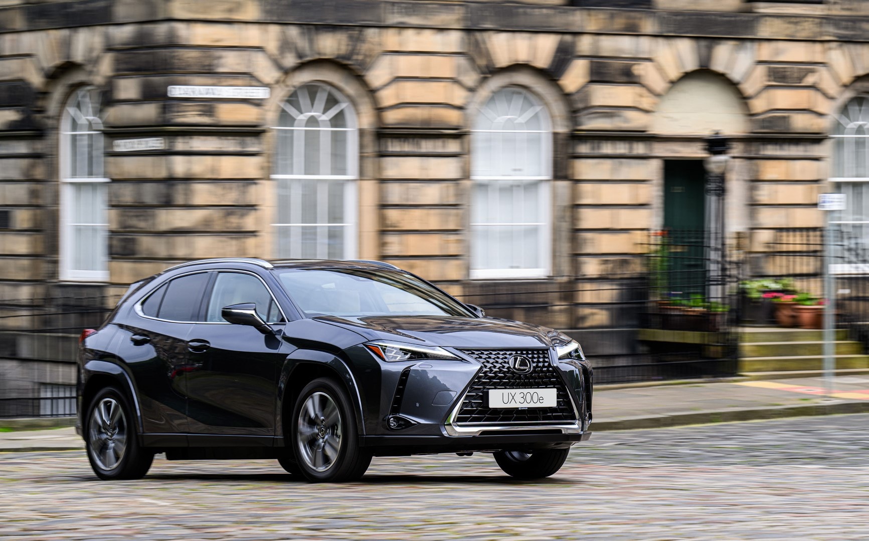 Imagen frontal y lateral del Lexus UX300e circulando en un área urbana.