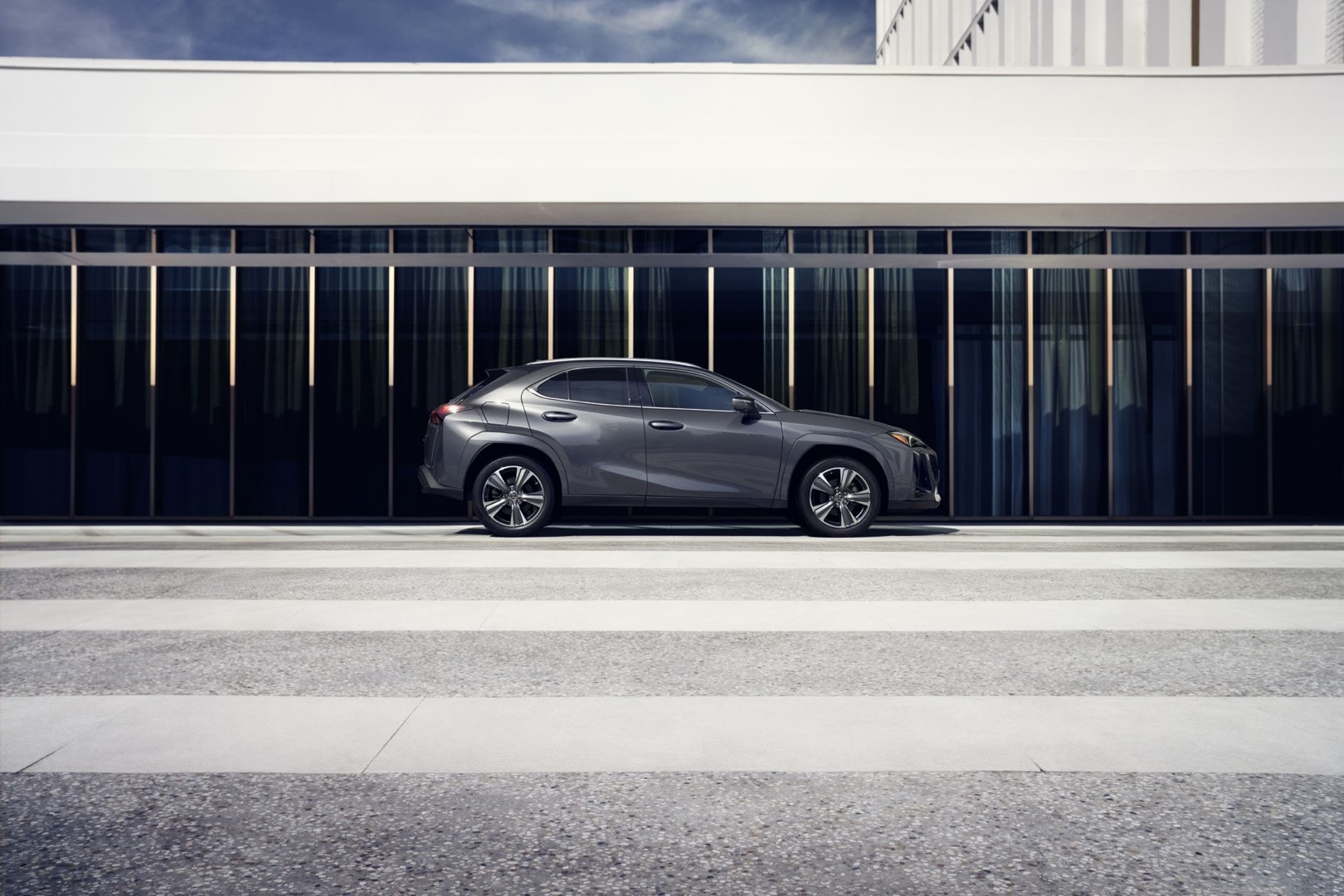 El Lexus UX300e exhibiendo su diseño lateral frente a arquitectura contemporánea.