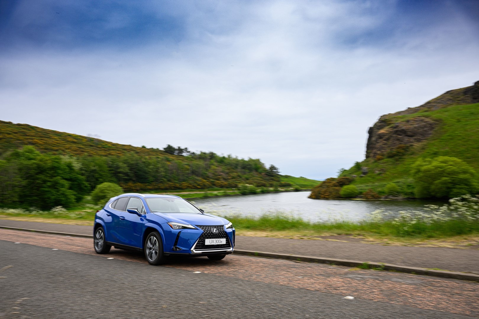 Lexus UX300e estacionado en un entorno natural, enfocado en su lateral.