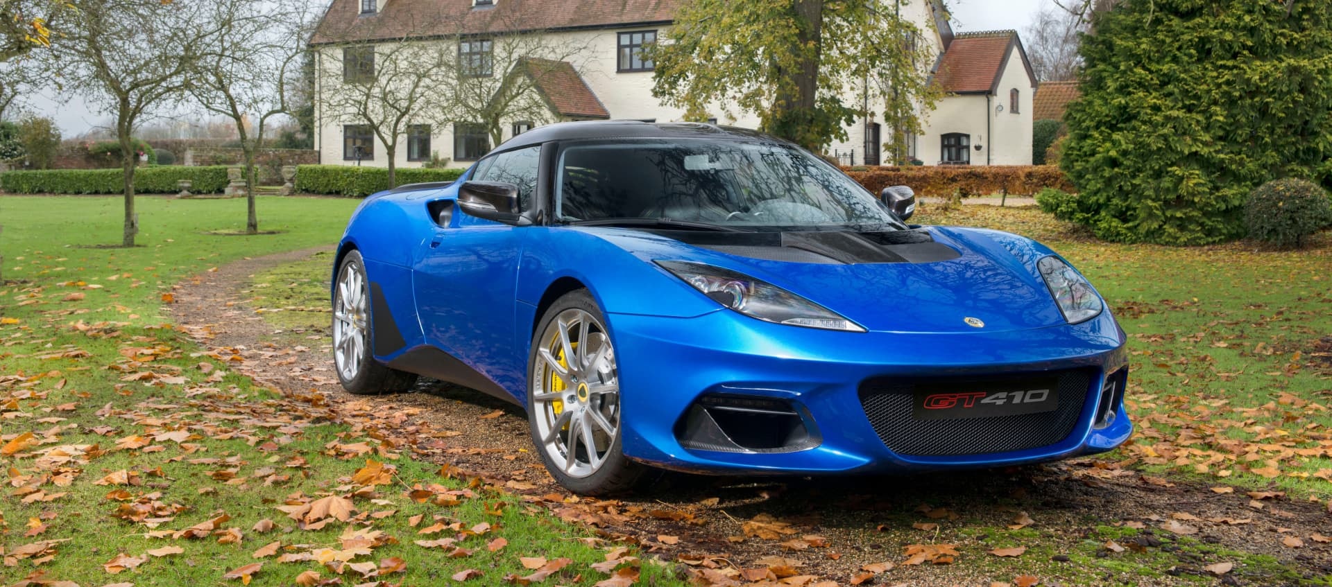 Lotus Evora en color azul, vista delantera y lateral en ambiente otoñal.