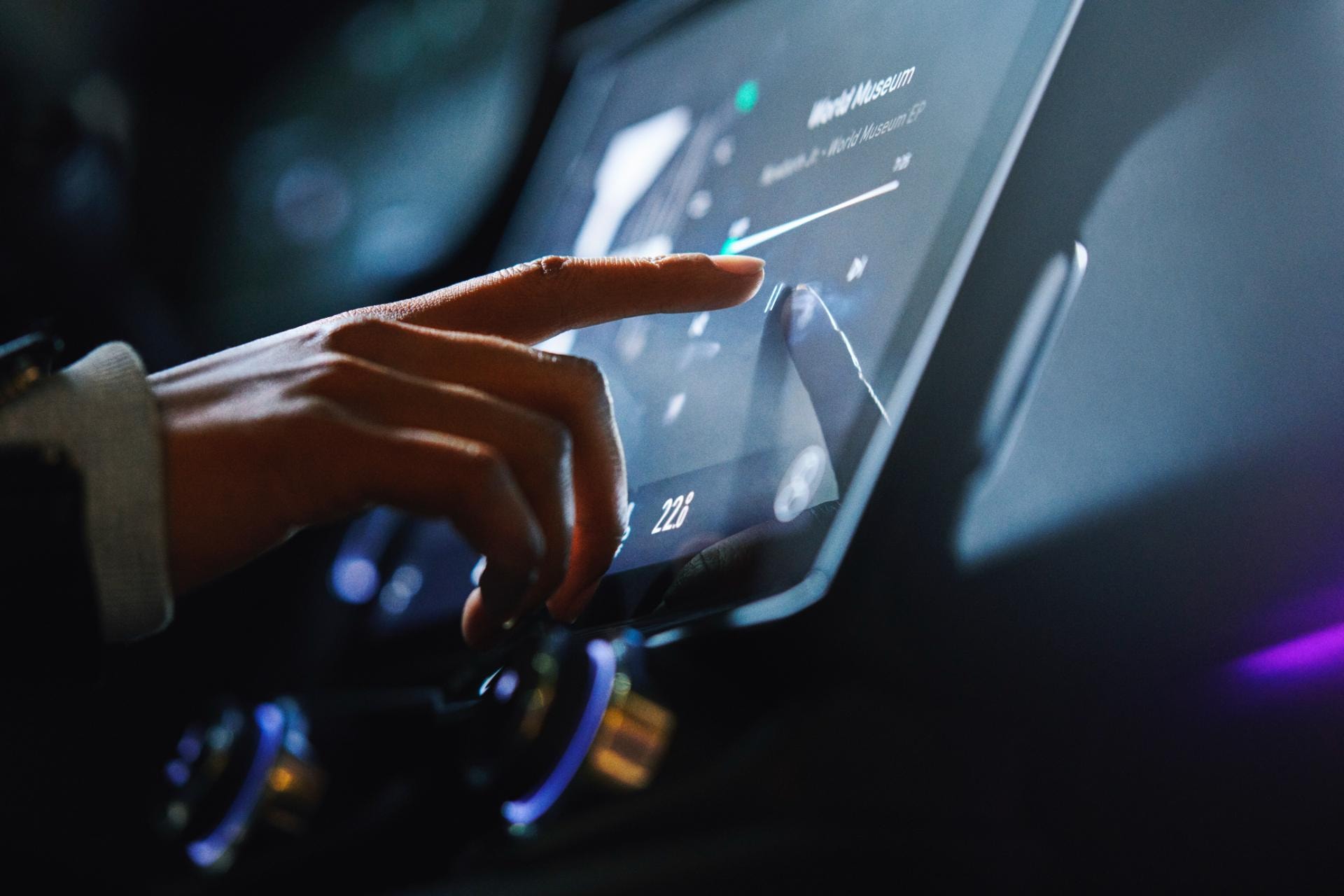 Mano interactuando con la pantalla táctil central del vehículo.