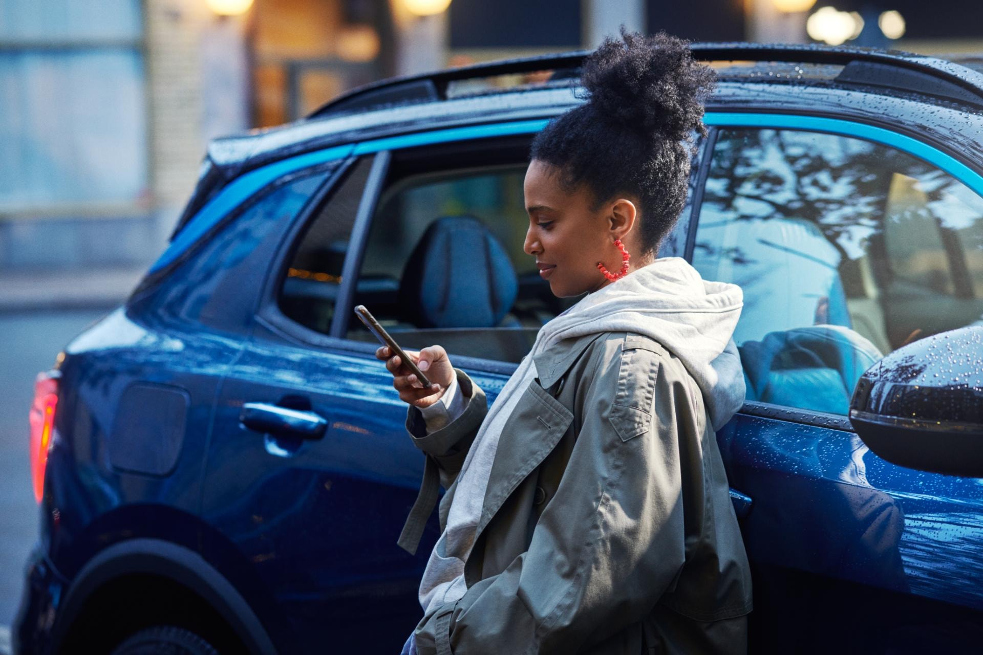 Usuario interactuando con su dispositivo móvil junto al Lynk & Co 01