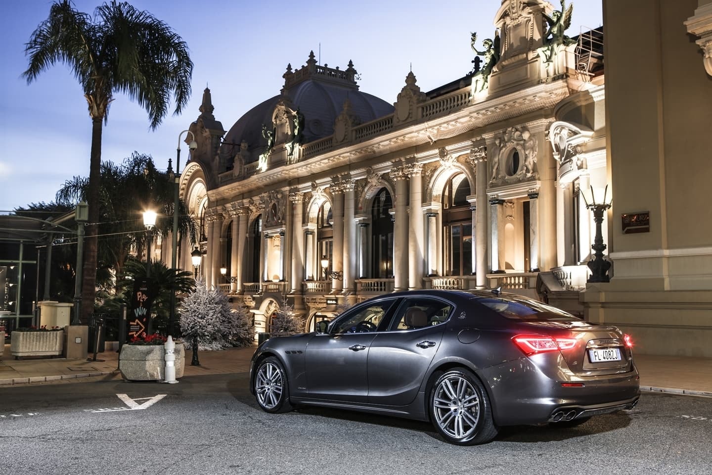 Vista trasera del Maserati Ghibli, con su diseño deportivo, ante un lujoso edificio nocturno.