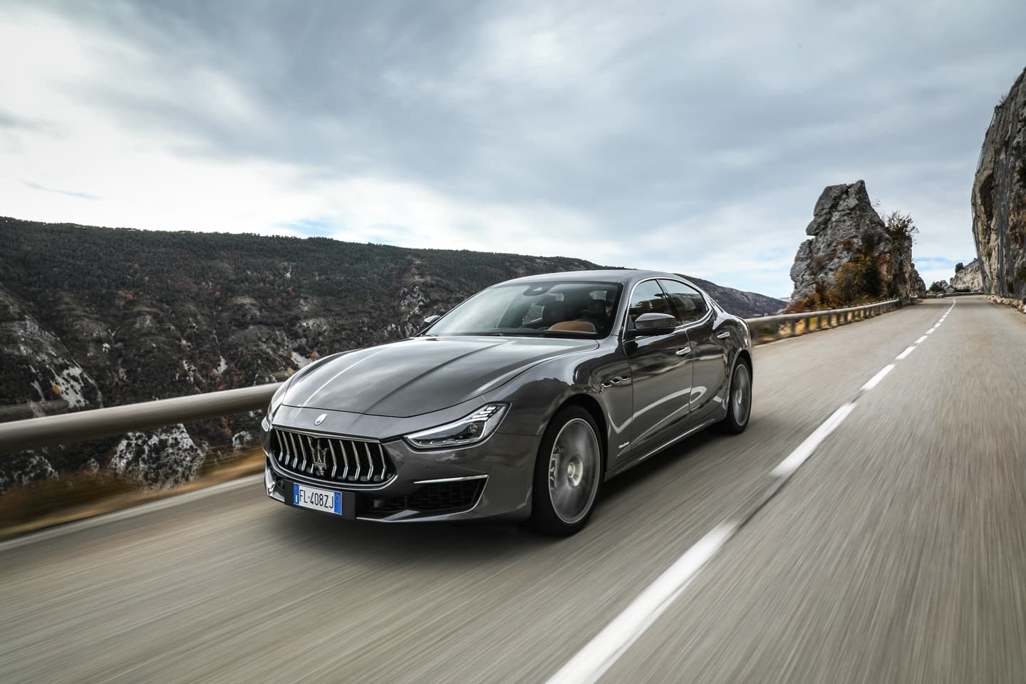 Perfil delantero del Ghibli mostrando su techo y líneas fluidas en un paisaje de carretera.