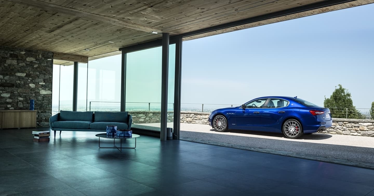 Imagen lateral del Maserati Ghibli que refleja su perfil elegante frente a una casa de diseño.
