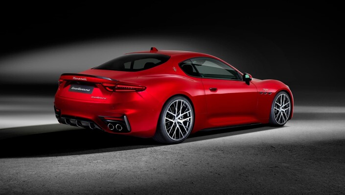 Vista lateral y trasera del Maserati GranTurismo en rojo, exhibiendo su diseño deportivo. Vista lateral y trasera del Maserati GranTurismo en rojo, exhibiendo su diseño deportivo.