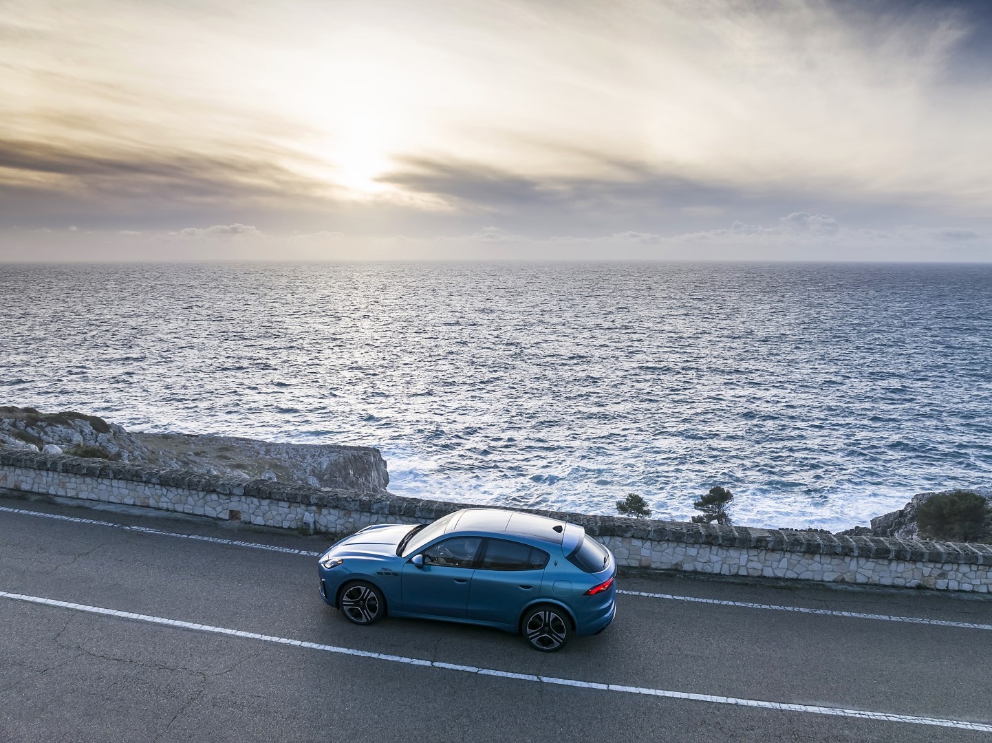 Perfil lateral del Maserati Grecale eléctrico a lo largo de la costa al atardecer.