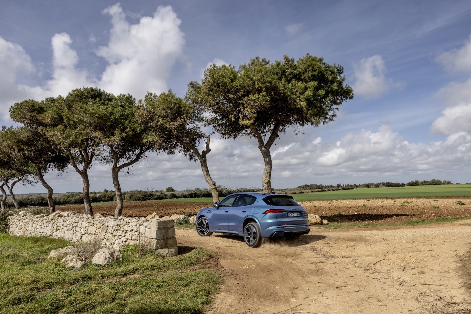 Vista lateral y trasera del Maserati Grecale en un paisaje campestre.