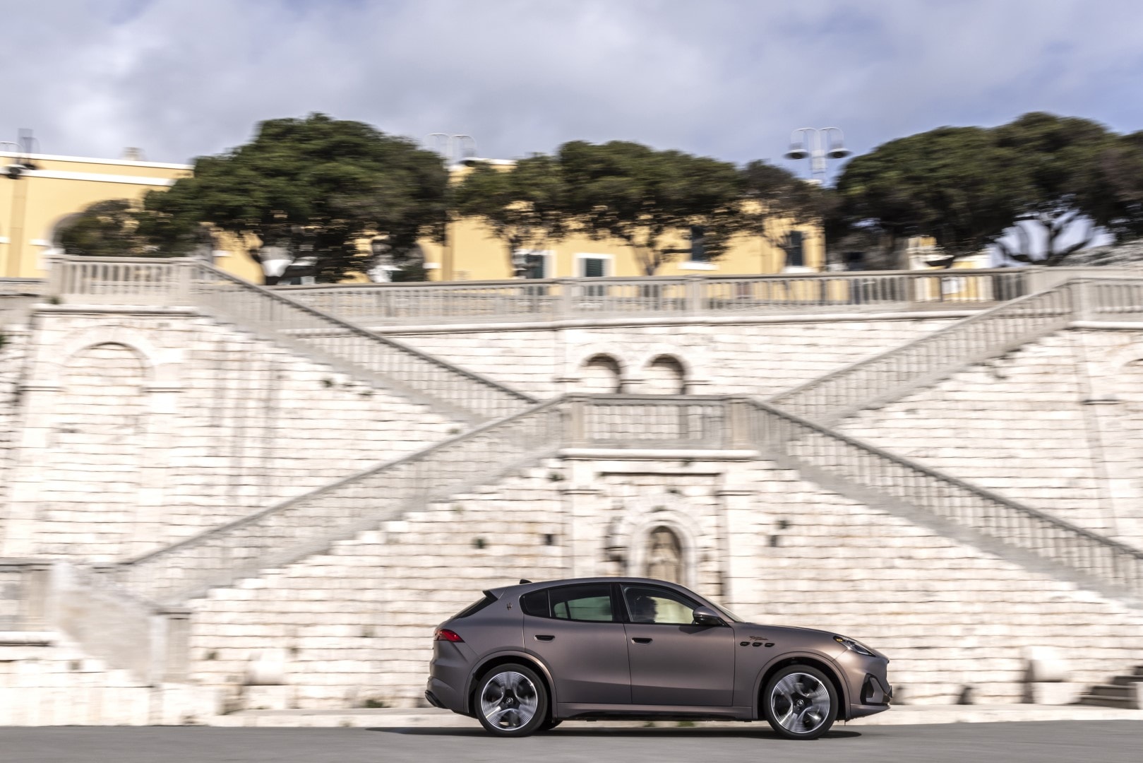 Vista lateral del Maserati Grecale ante un fondo arquitectónico imponente.