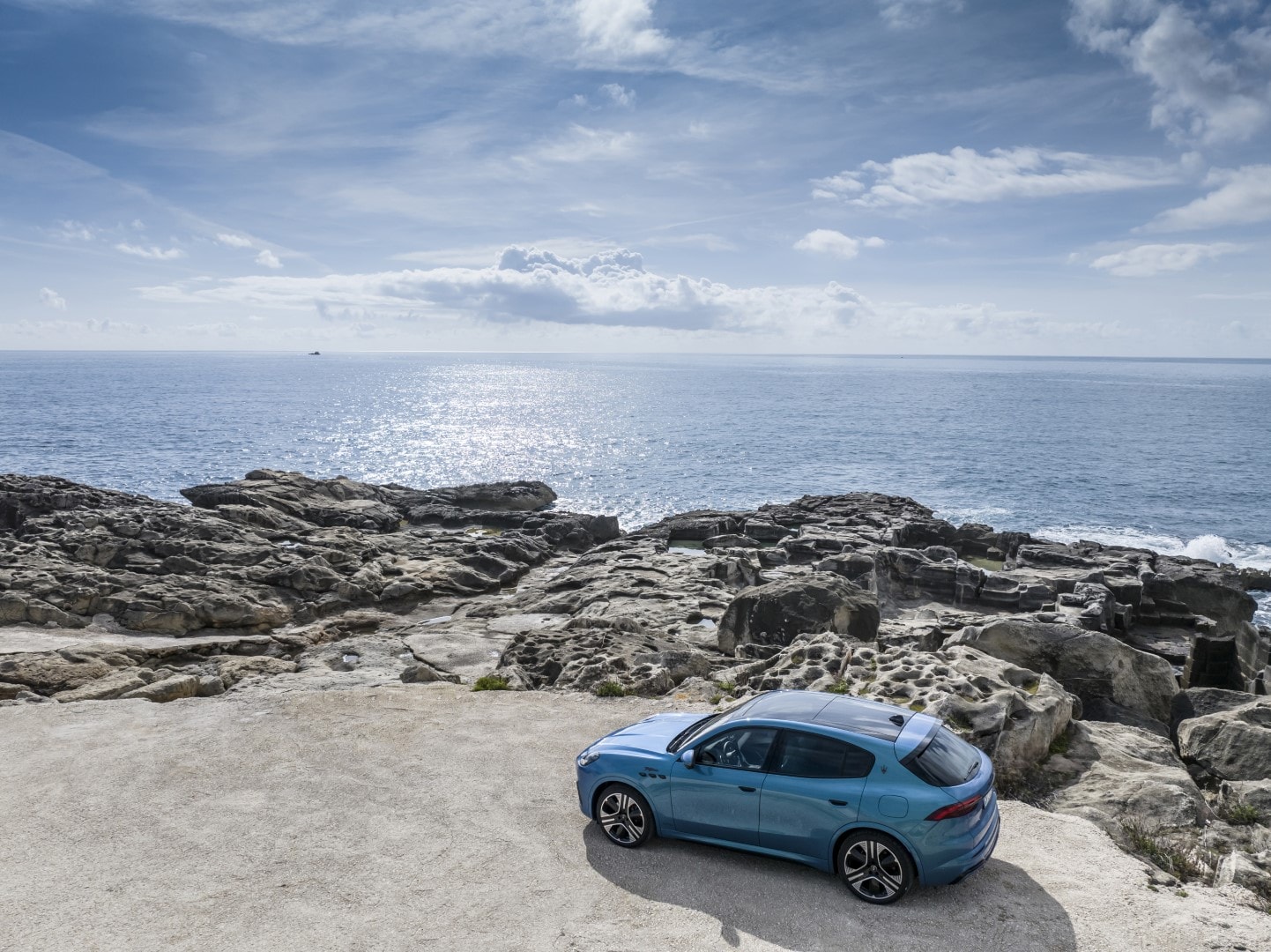 Perspectiva del Maserati Grecale en una ubicación costera rocosa, destacando su parte trasera y lateral.