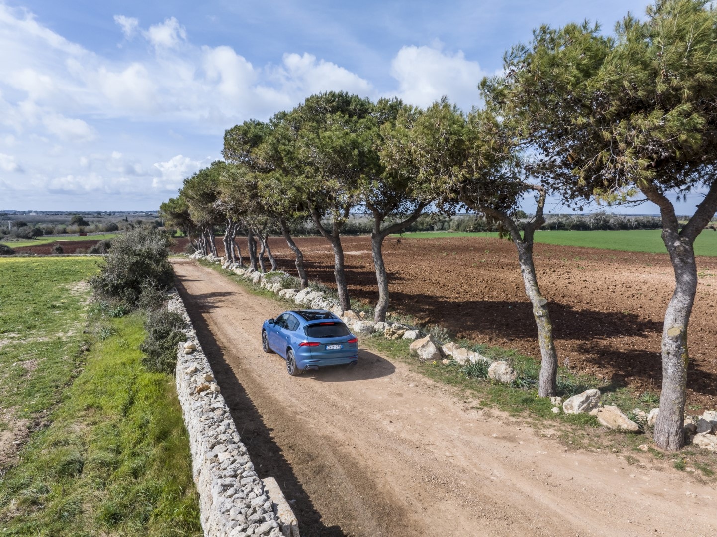 Imagen de la parte trasera del Maserati Grecale explorando caminos rurales.