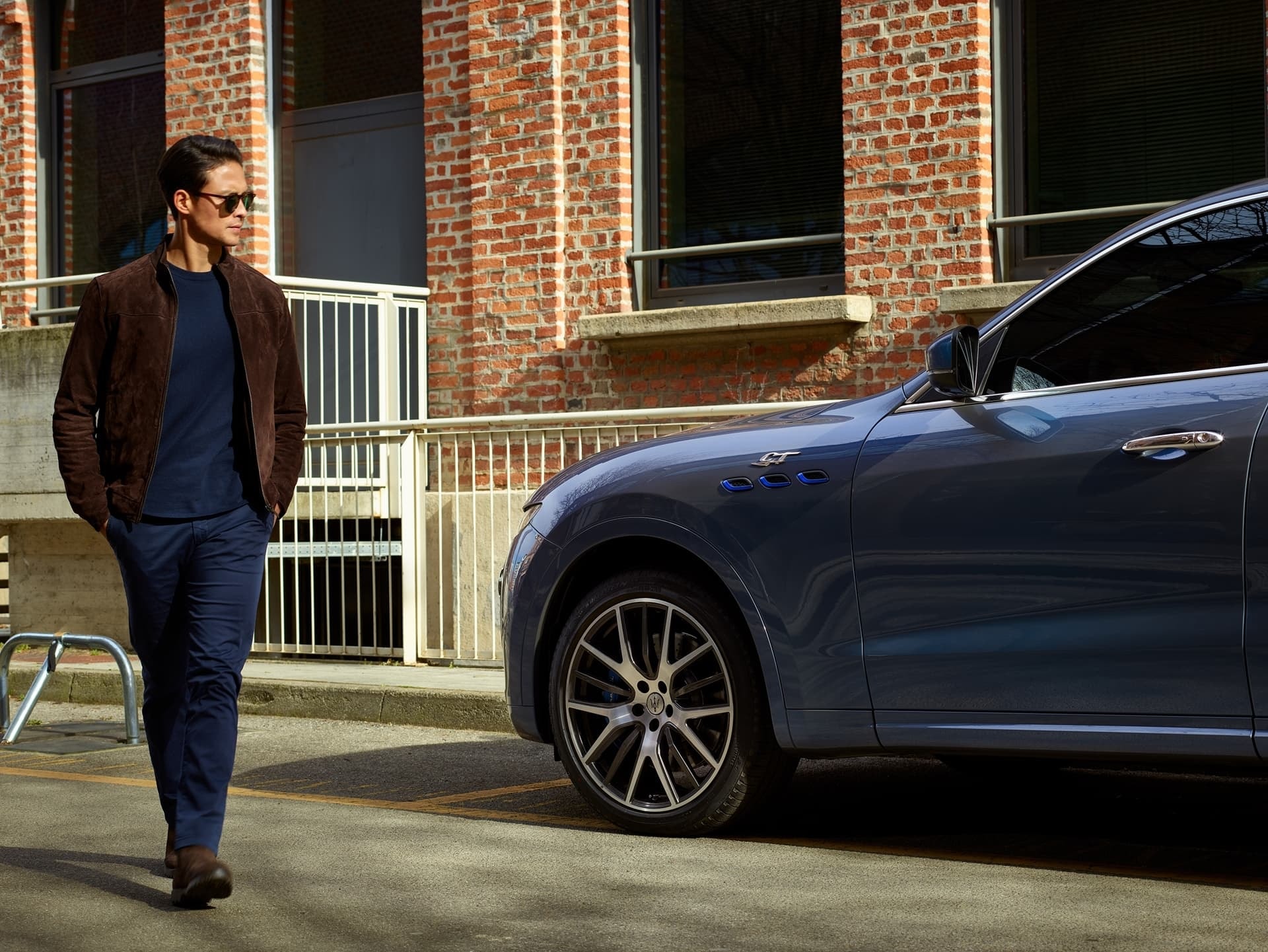 Un Maserati Levante azul junto a un hombre en un ambiente urbano.