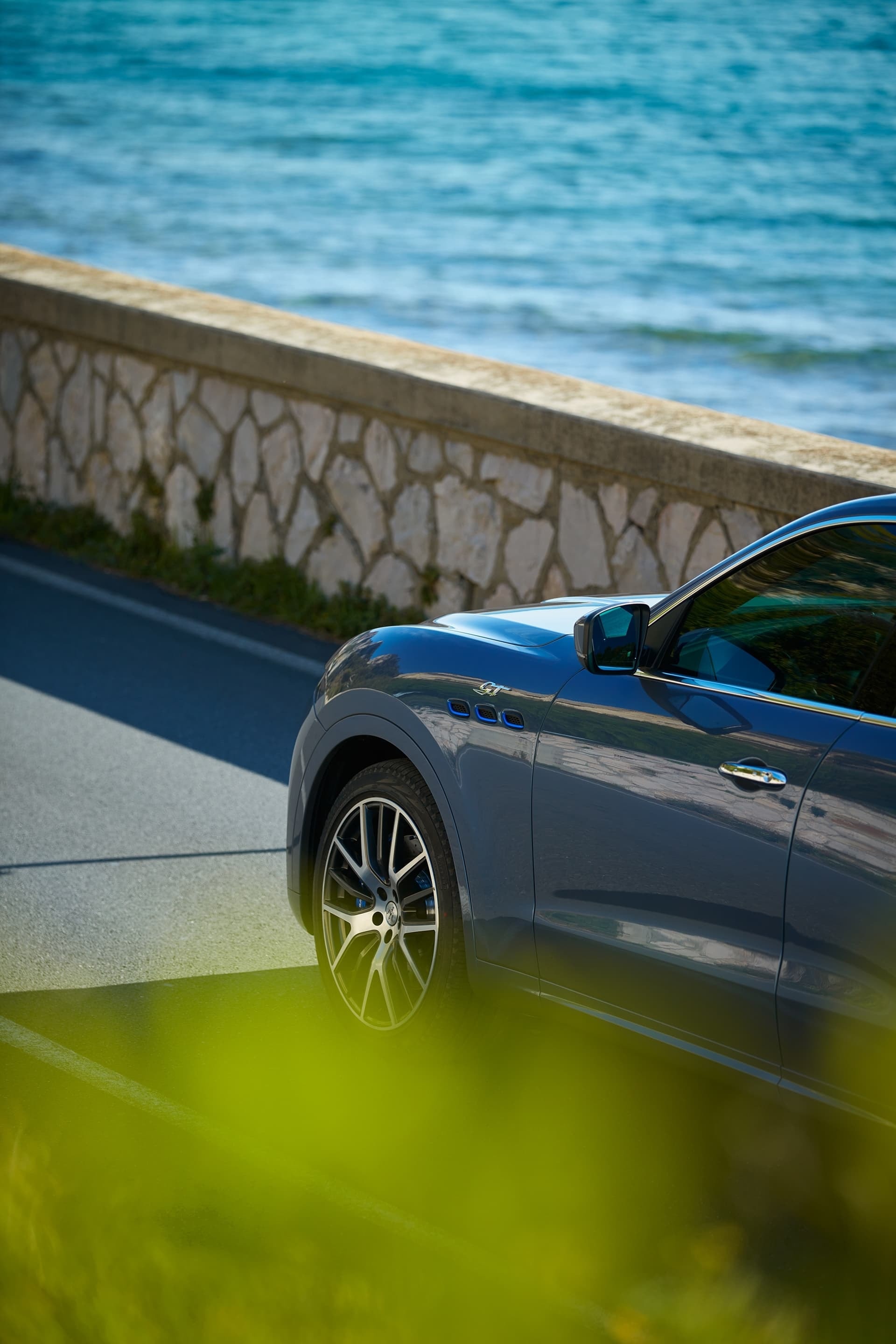 Vista parcial lateral del Maserati Levante cerca del mar.