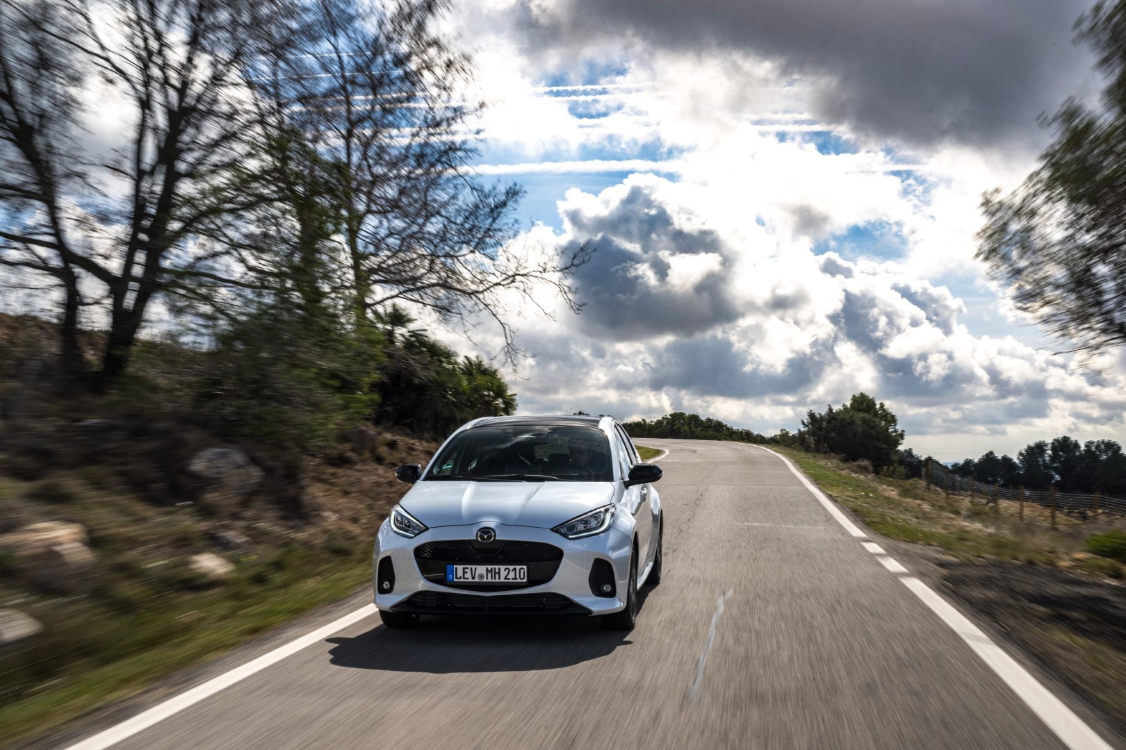 Imagen dinámica del Mazda 2 híbrido en carretera abierta, transmite velocidad y eficiencia.