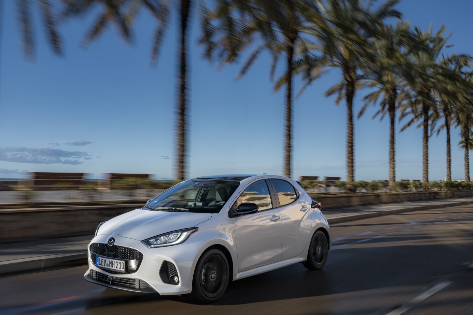 Imagen del Mazda 2 híbrido capturando su estética lateral en tránsito.