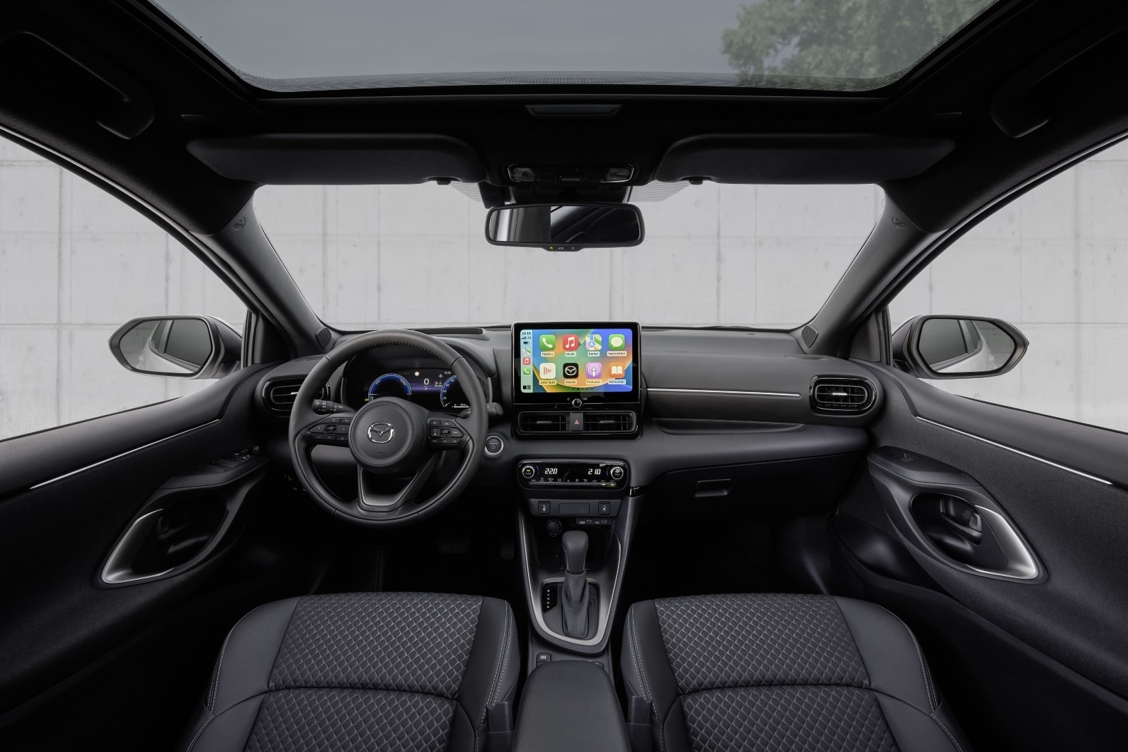 Vista frontal del interior que muestra volante y pantalla táctil