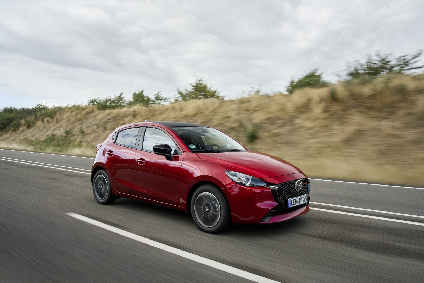 Vista lateral en movimiento del Mazda 2 destacando su diseño fluido.