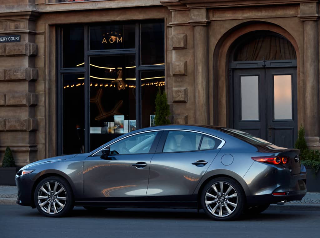 Perfil lateral del Mazda 3 SportSedán estacionado en la calle.