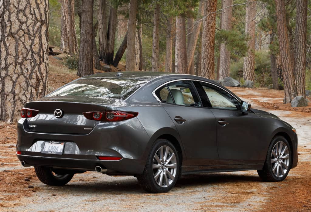 Perfil trasero y lateral del Mazda 3 SportSedán en entorno forestal.