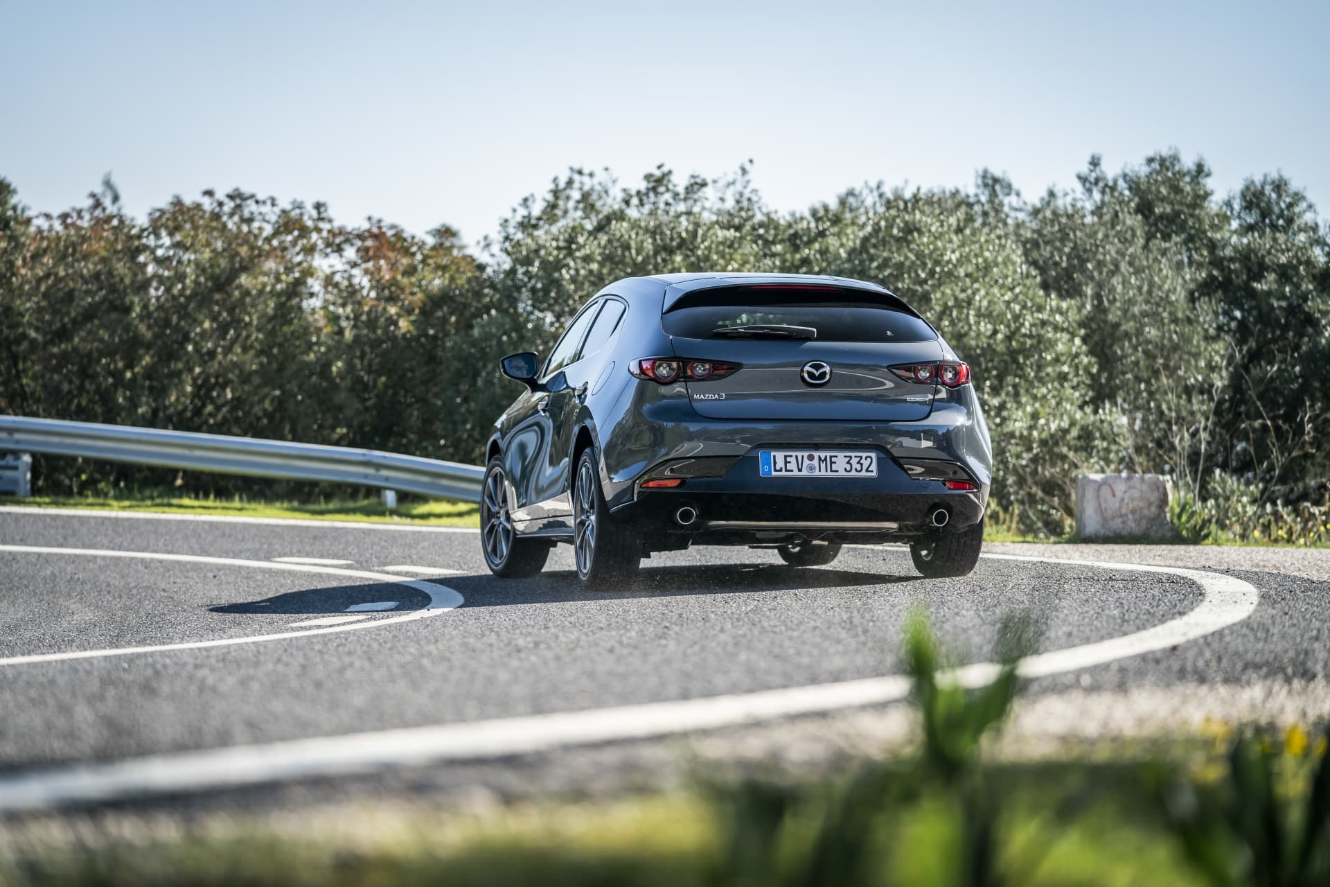 Vista trasera del Mazda 3 negociando una curva, mostrando su diseño y rendimiento.