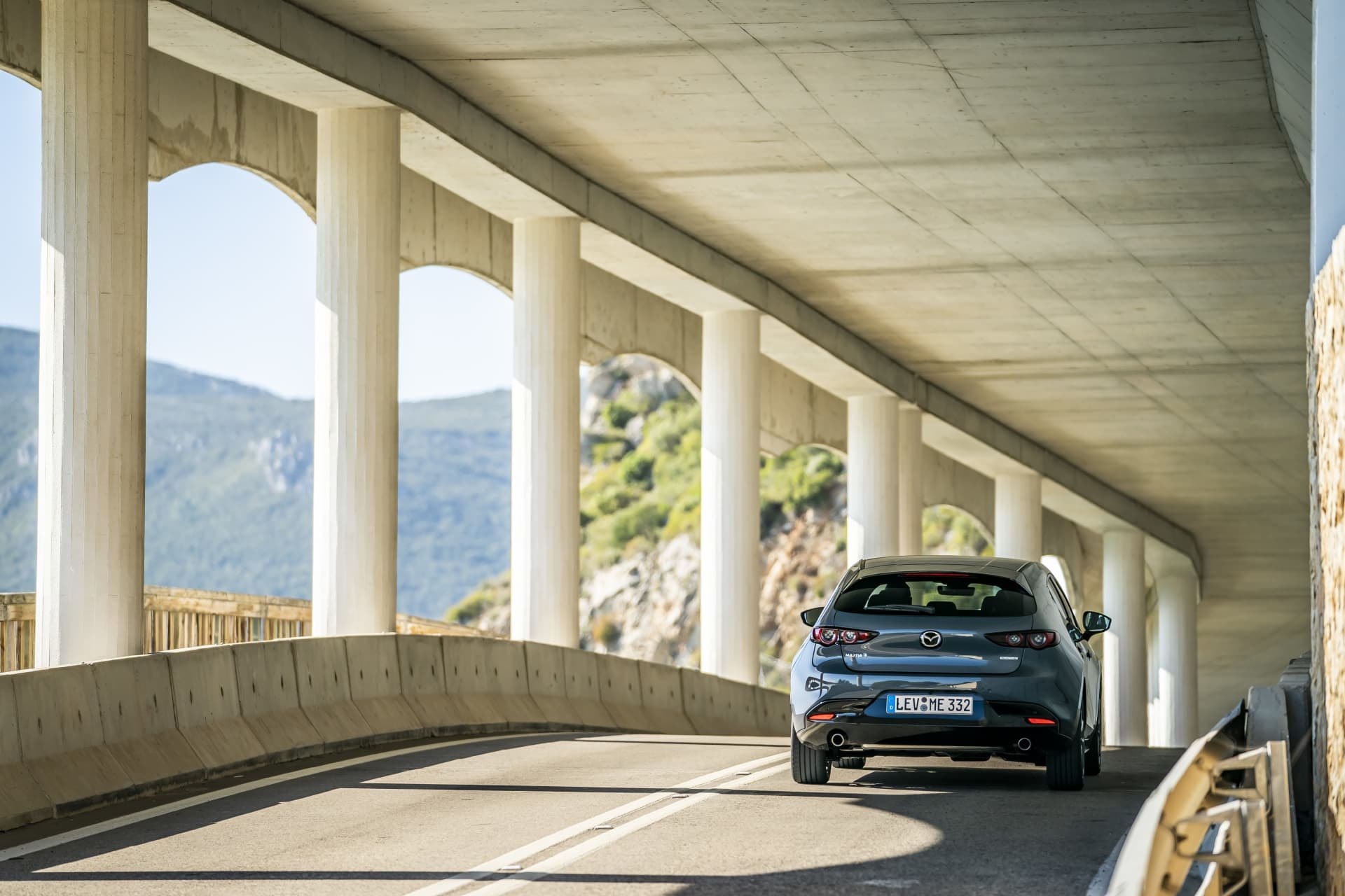 Trasera del Mazda 3 bajo un puente, mostrando una perspectiva arquitectónica y diseño.