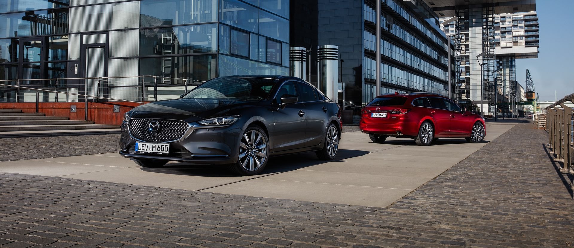 Imagen frontal de dos Mazda 6 enfilados en ambiente urbano.