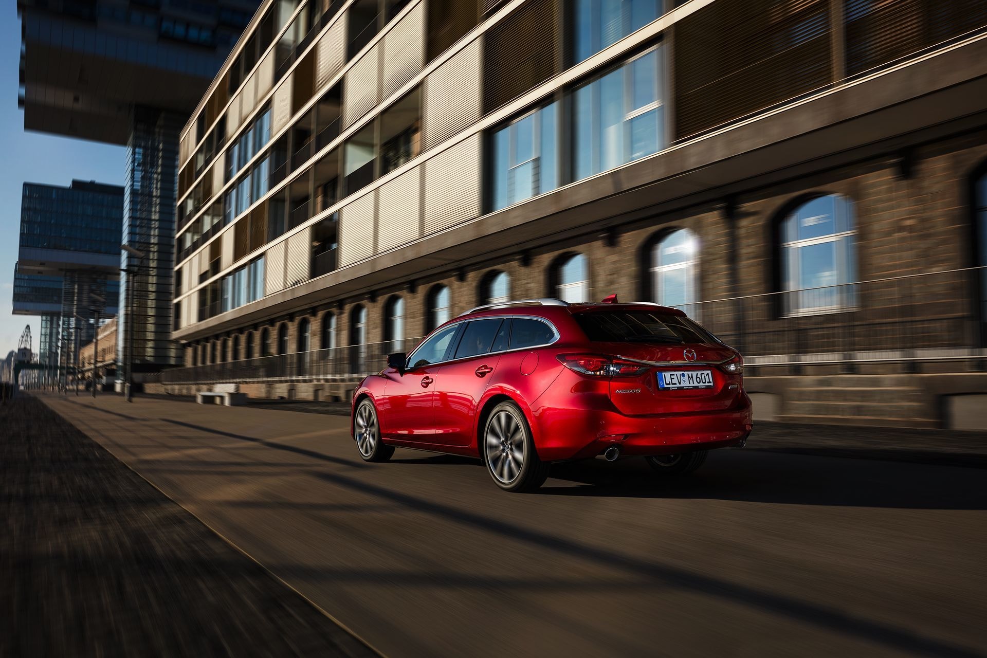 Trasera de un Mazda 6 rojo en movimiento por un entorno urbano.