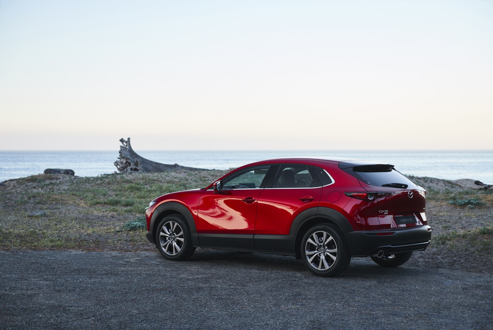 Fotografía que captura la trasera y lateral del Mazda CX-30 frente a un paisaje costero.